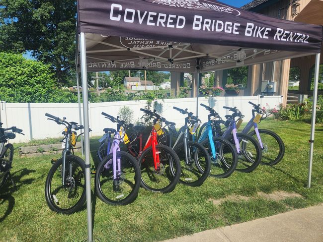 Covered Bridge Bike Rental stand with colorful bikes on display.
