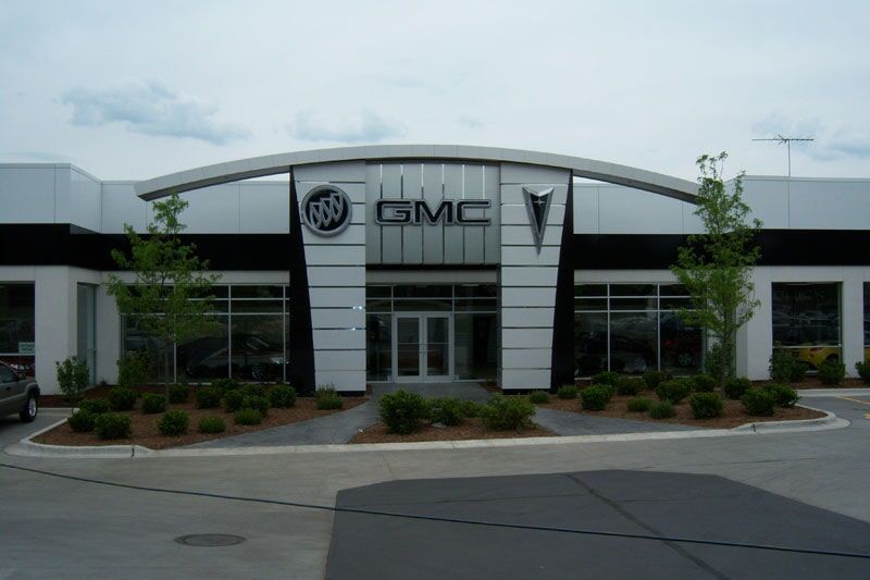 A construction sign is hanging on a fence next to a hole in the ground.