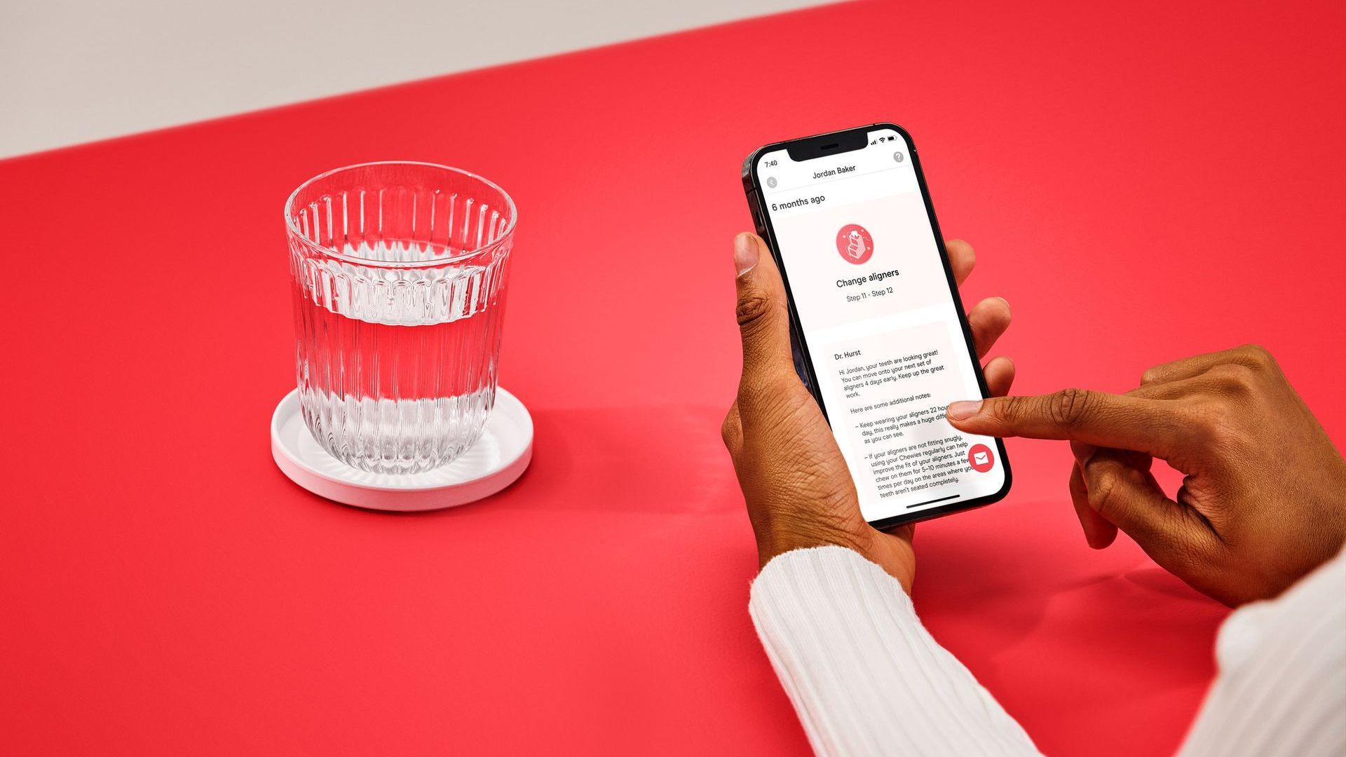 A person is using a cell phone next to a glass of water.