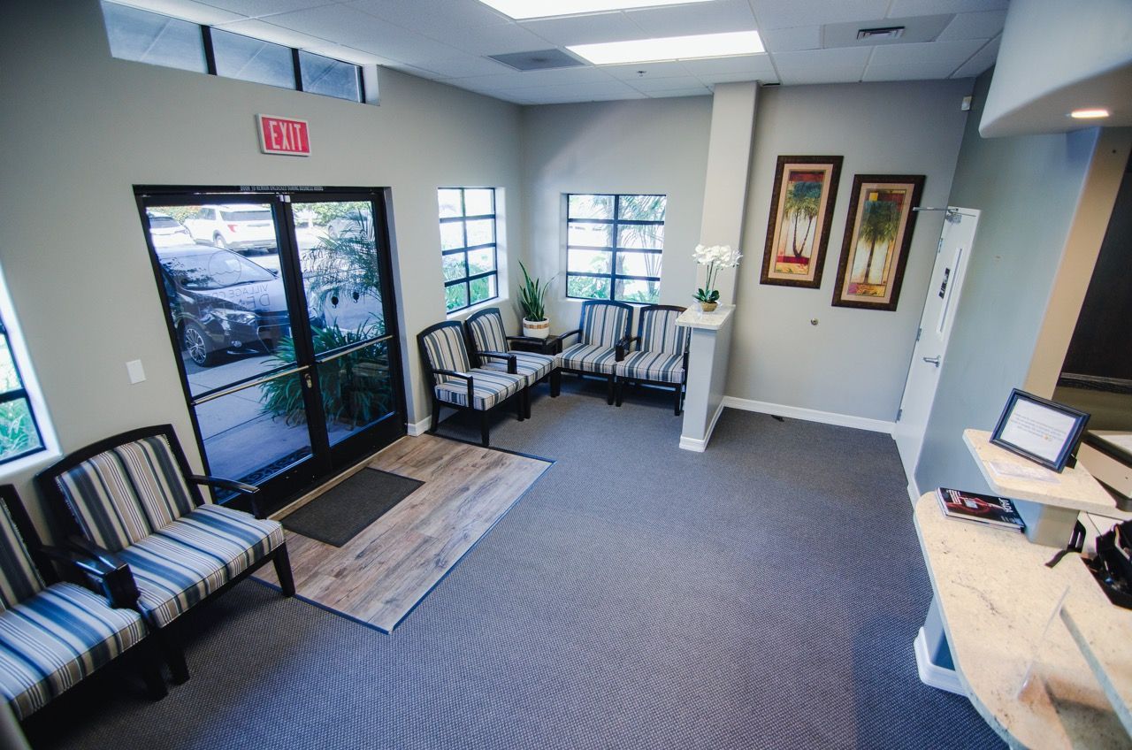 A waiting room with a lot of chairs and a red exit sign.