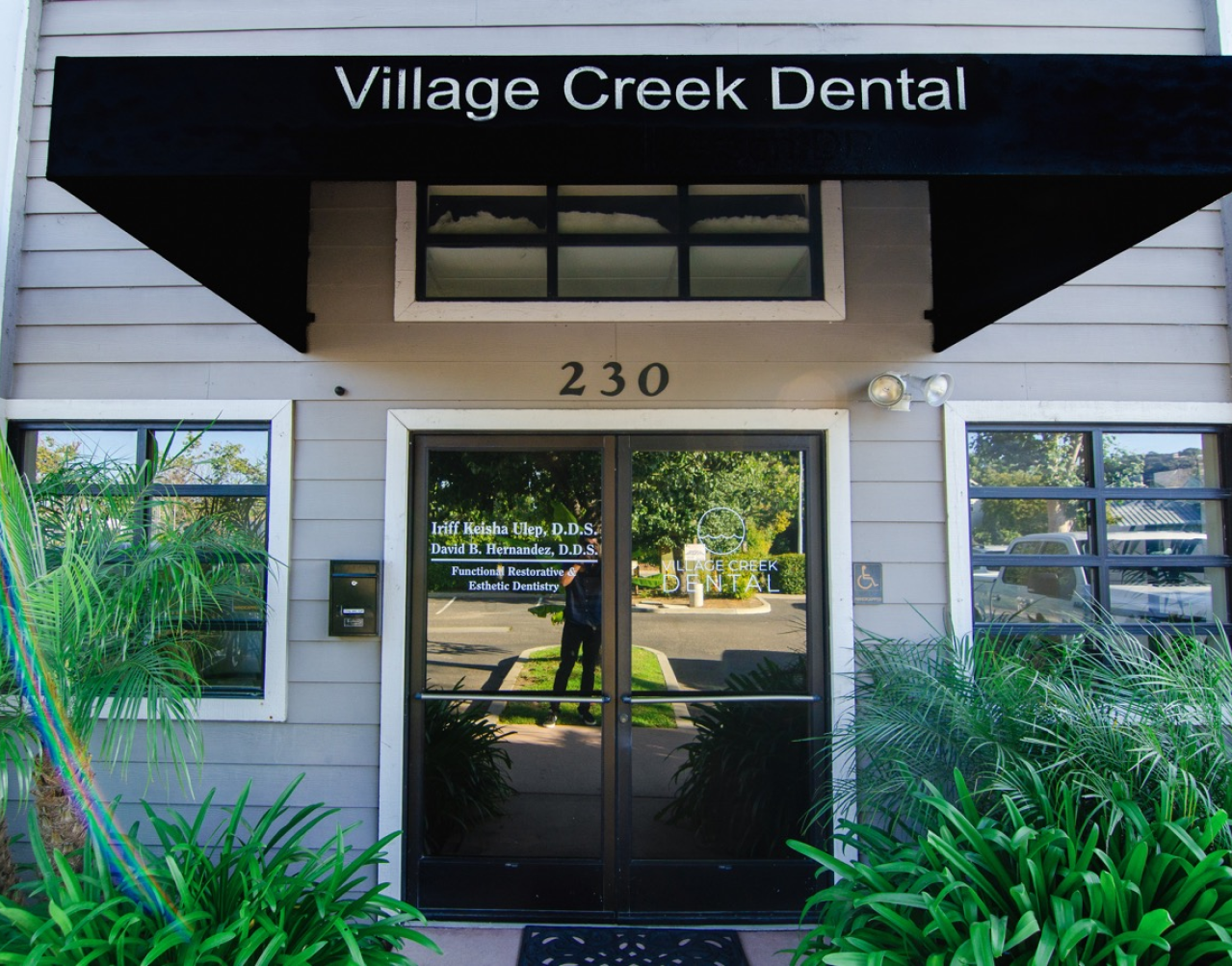 The entrance to village creek dental has a black awning over the door
