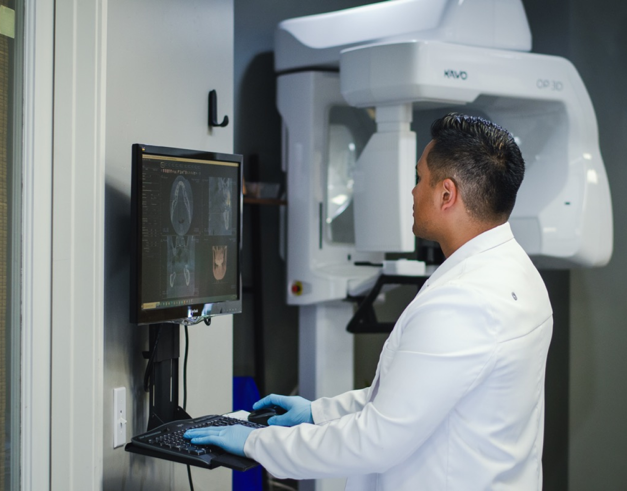 A man in a lab coat is working on a computer.