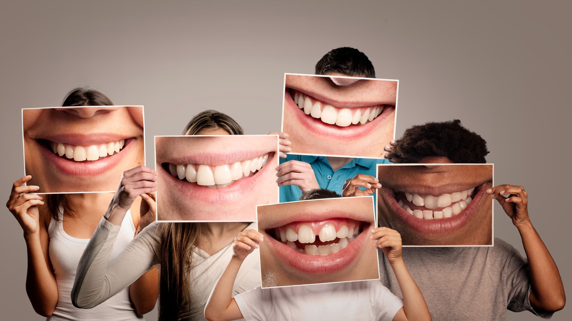 A group of people are holding pictures of their smiles in front of their faces.