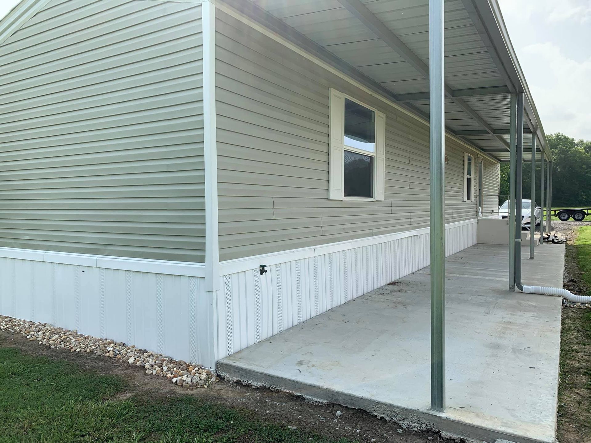 Mobile home with a concrete porch and metal awning. Green siding, white trim.
