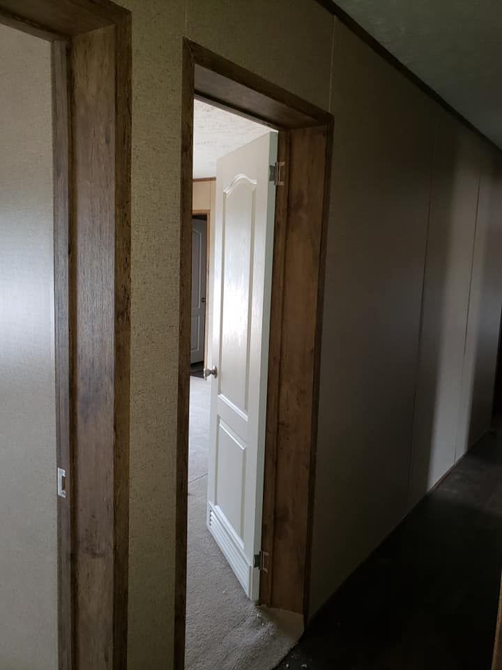 A hallway with a door open leading to a room.