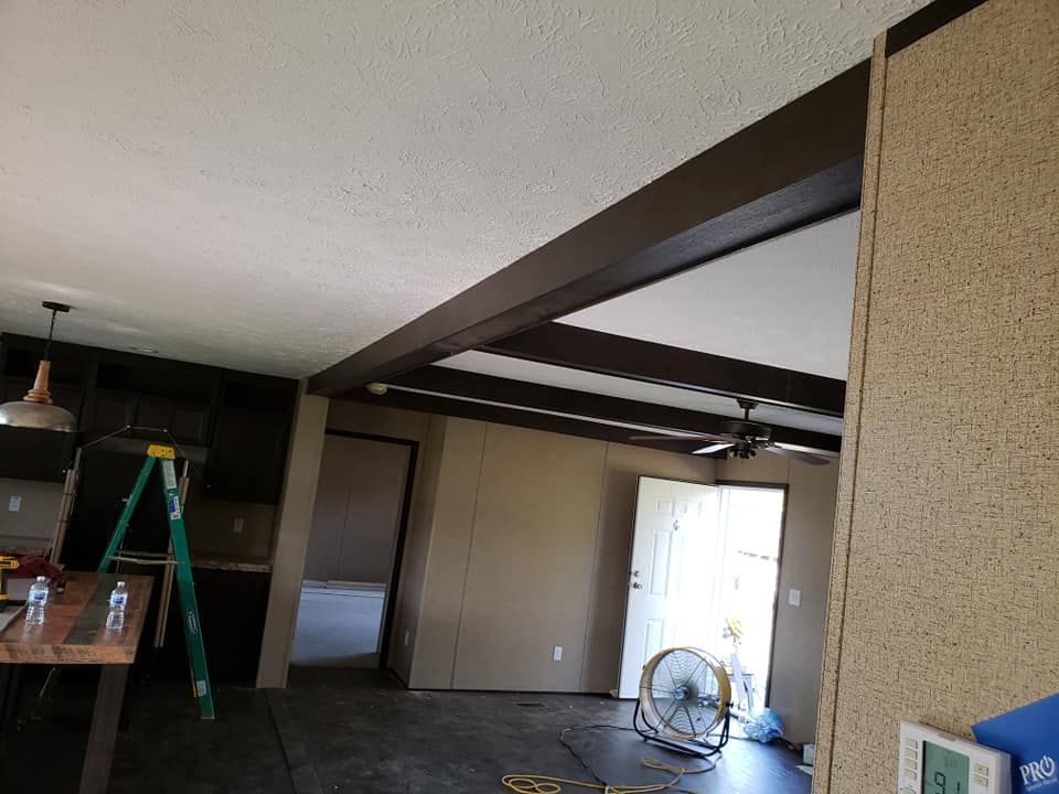 A living room with a ladder and a fan in it.
