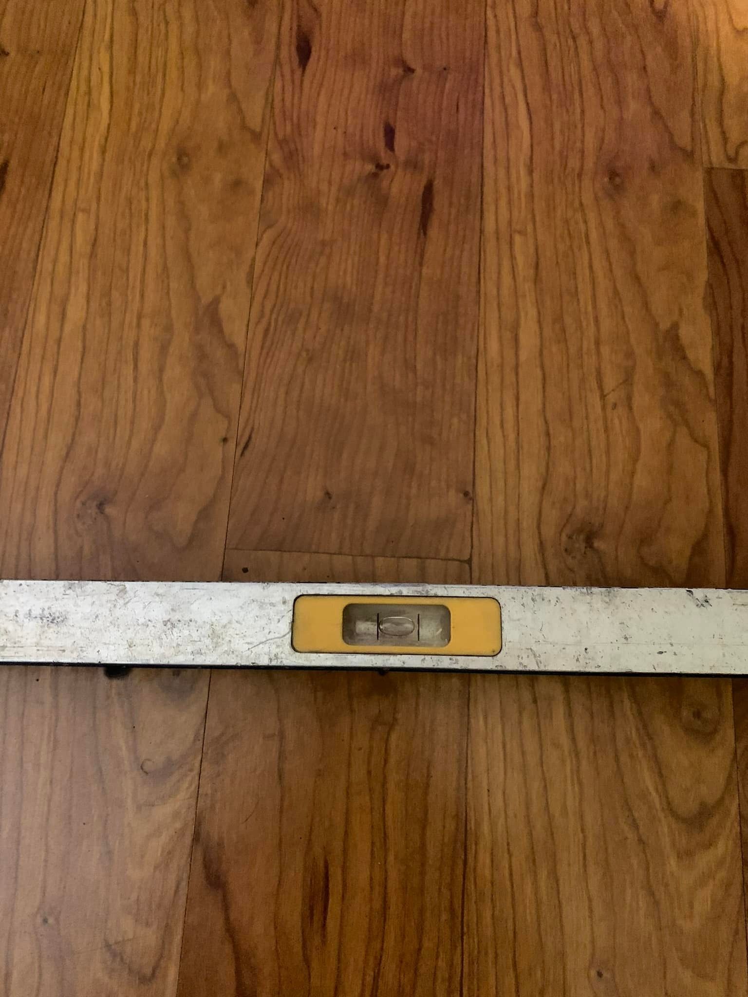 A level is sitting on a wooden floor.