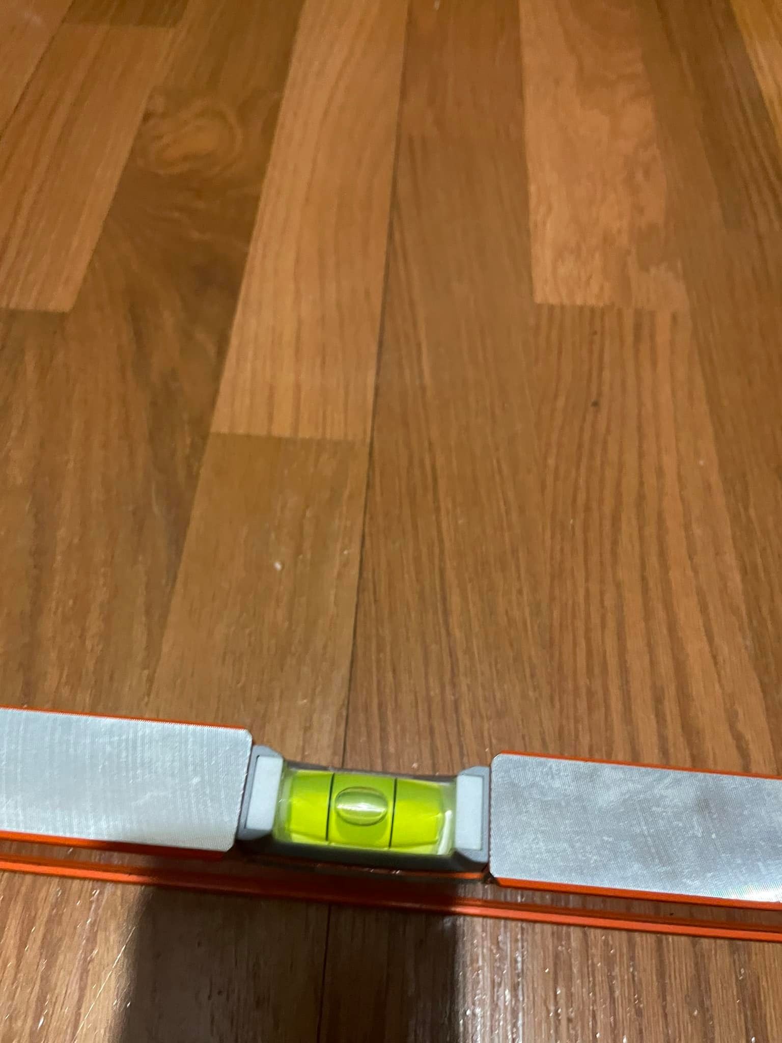 A level is sitting on top of a wooden floor.