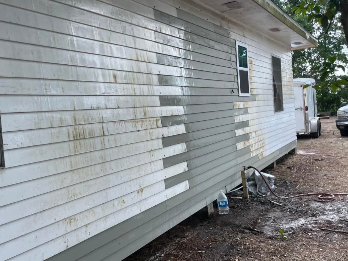 A white house with a gray siding is being painted.