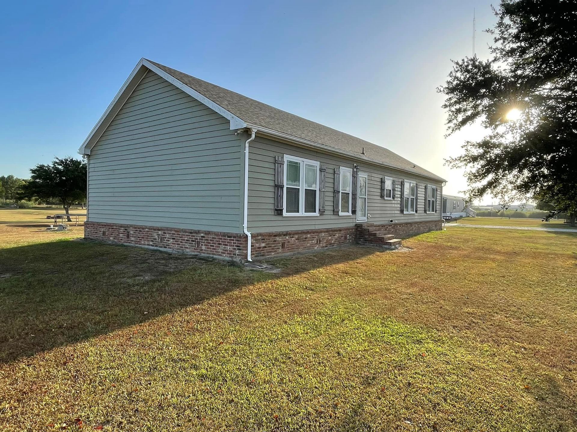 A small house is sitting in the middle of a grassy field.