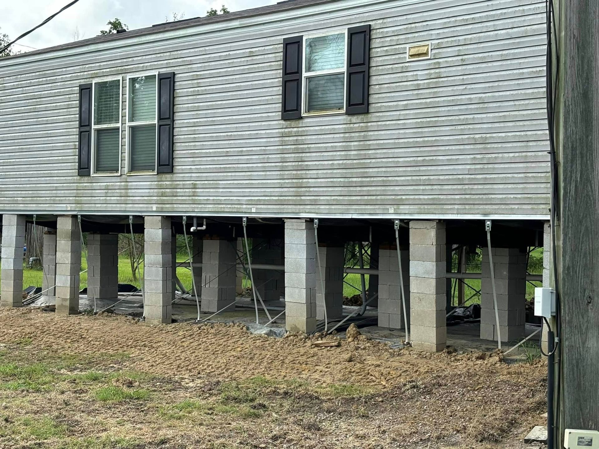 A mobile home is sitting on stilts in a field.