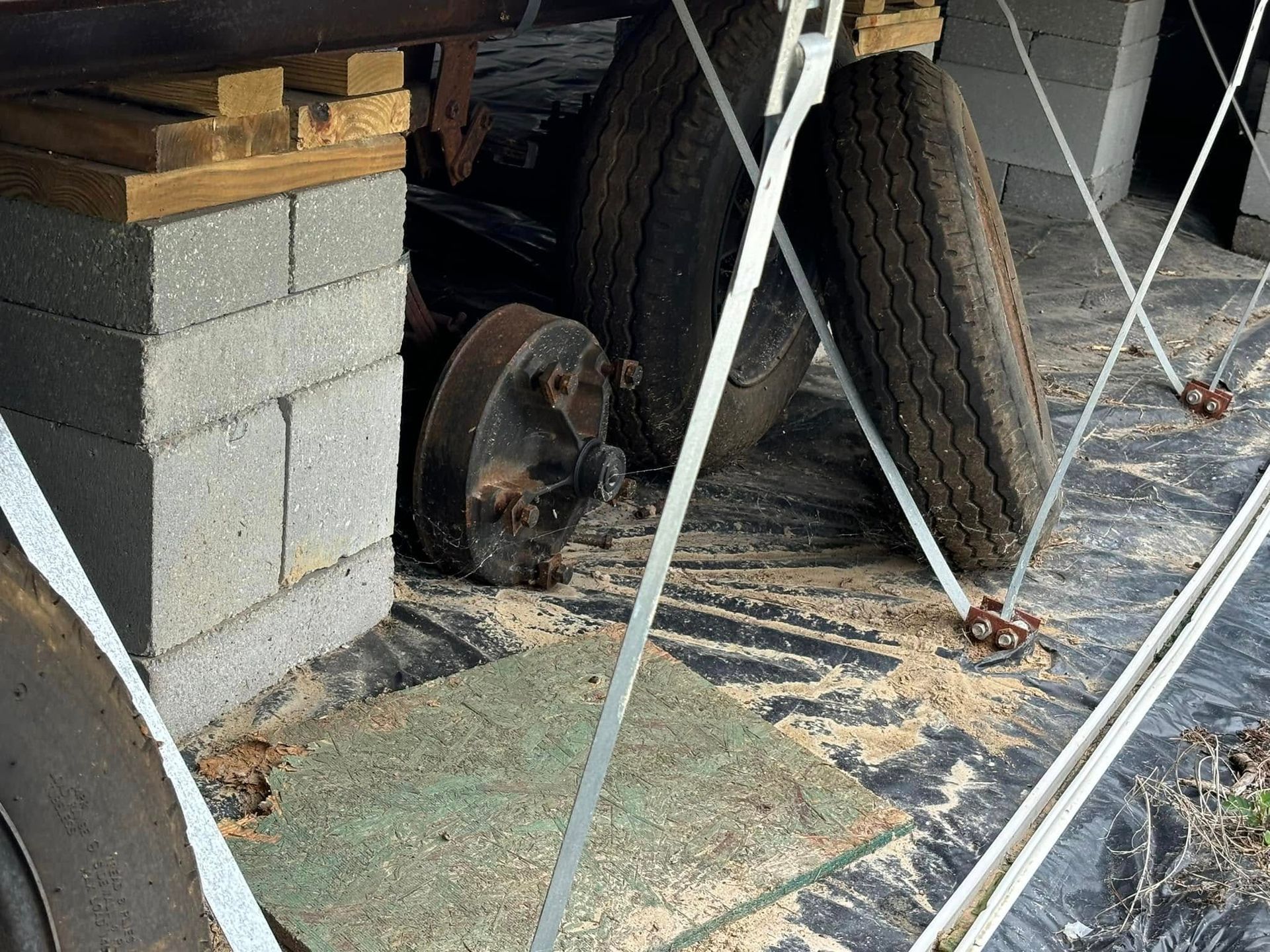 A bunch of tires are sitting on the ground next to a brick wall.