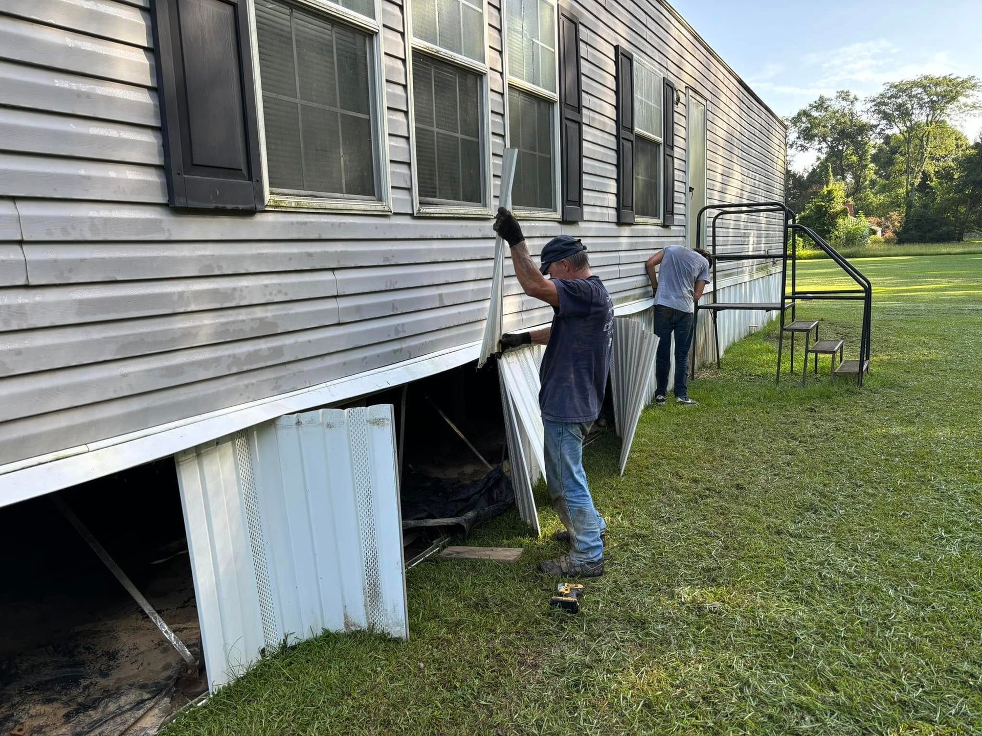 Two men are working on the side of a mobile home.