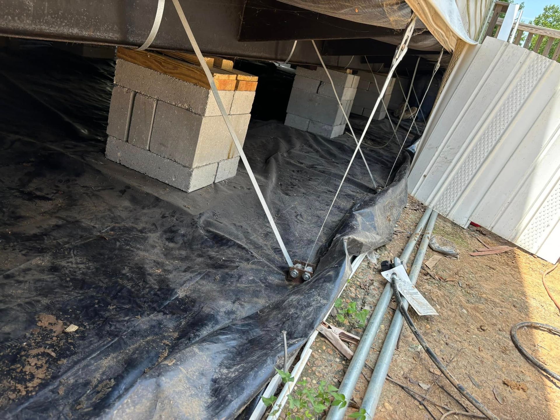 A concrete block is sitting on top of a black tarp under a house.