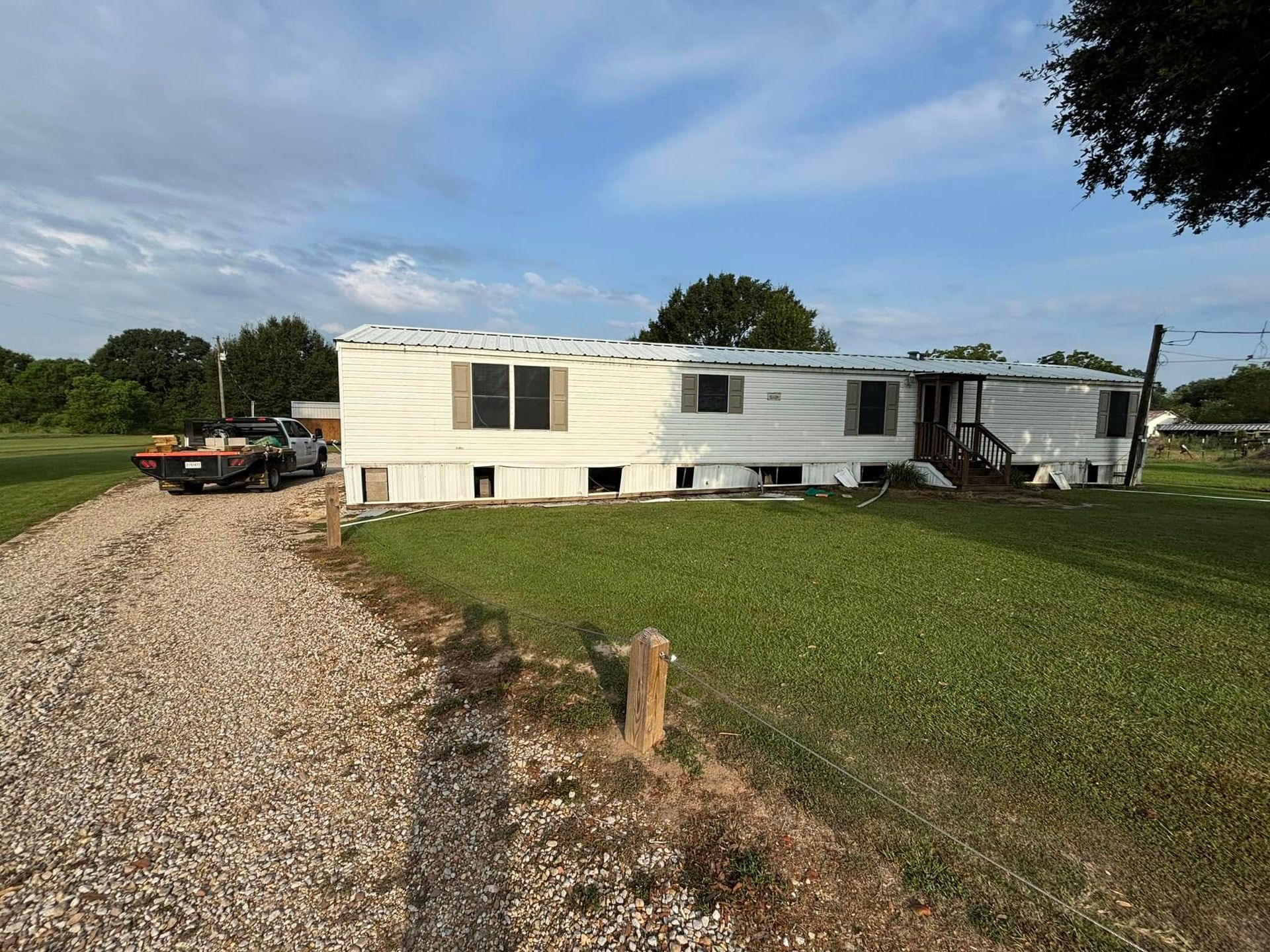 A mobile home is parked on the side of a gravel road.