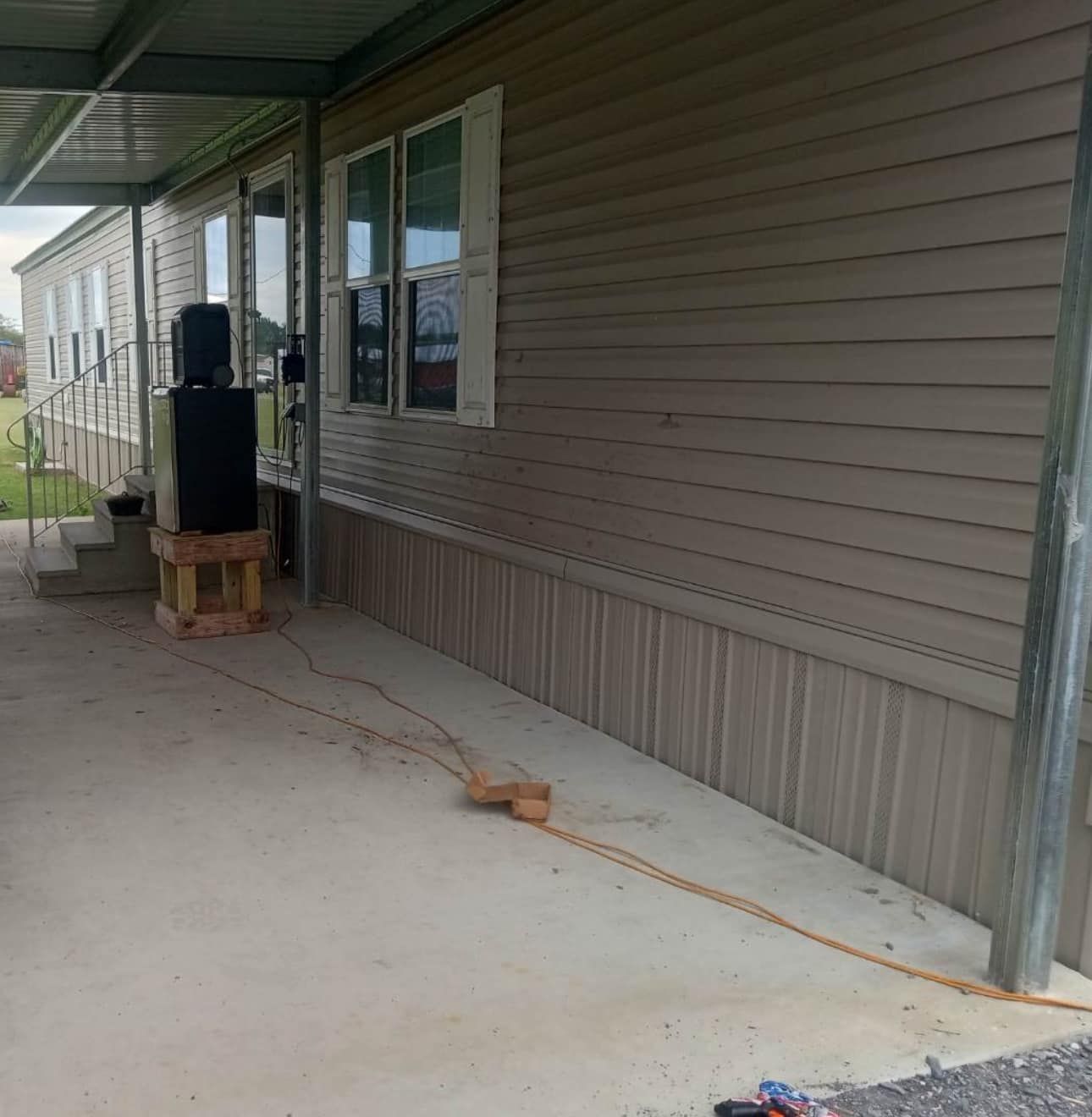 A mobile home with a covered porch and a lot of windows.