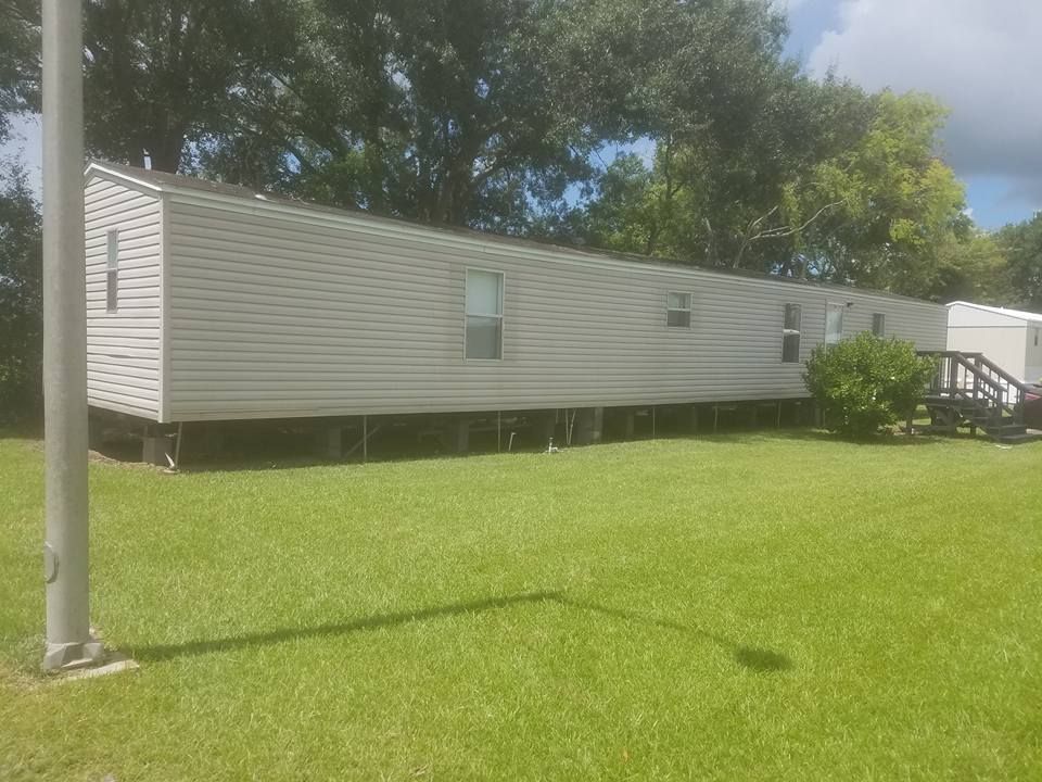 Mobile home on green grass under a cloudy sky.