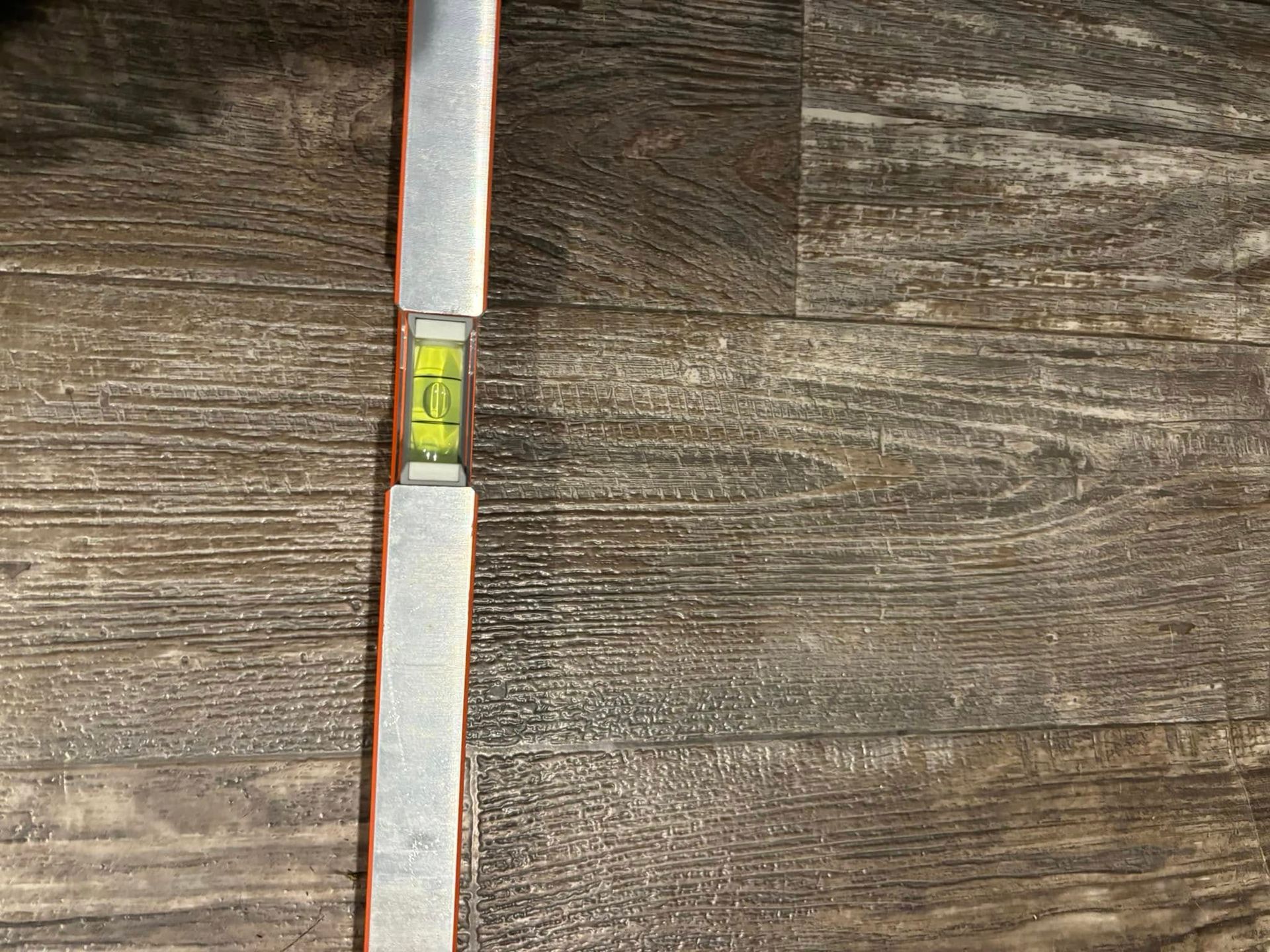 A level is sitting on top of a wooden floor.