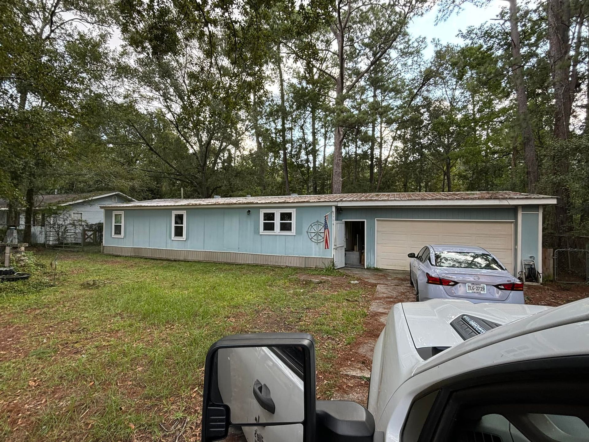 A white truck is parked in front of a blue mobile home.