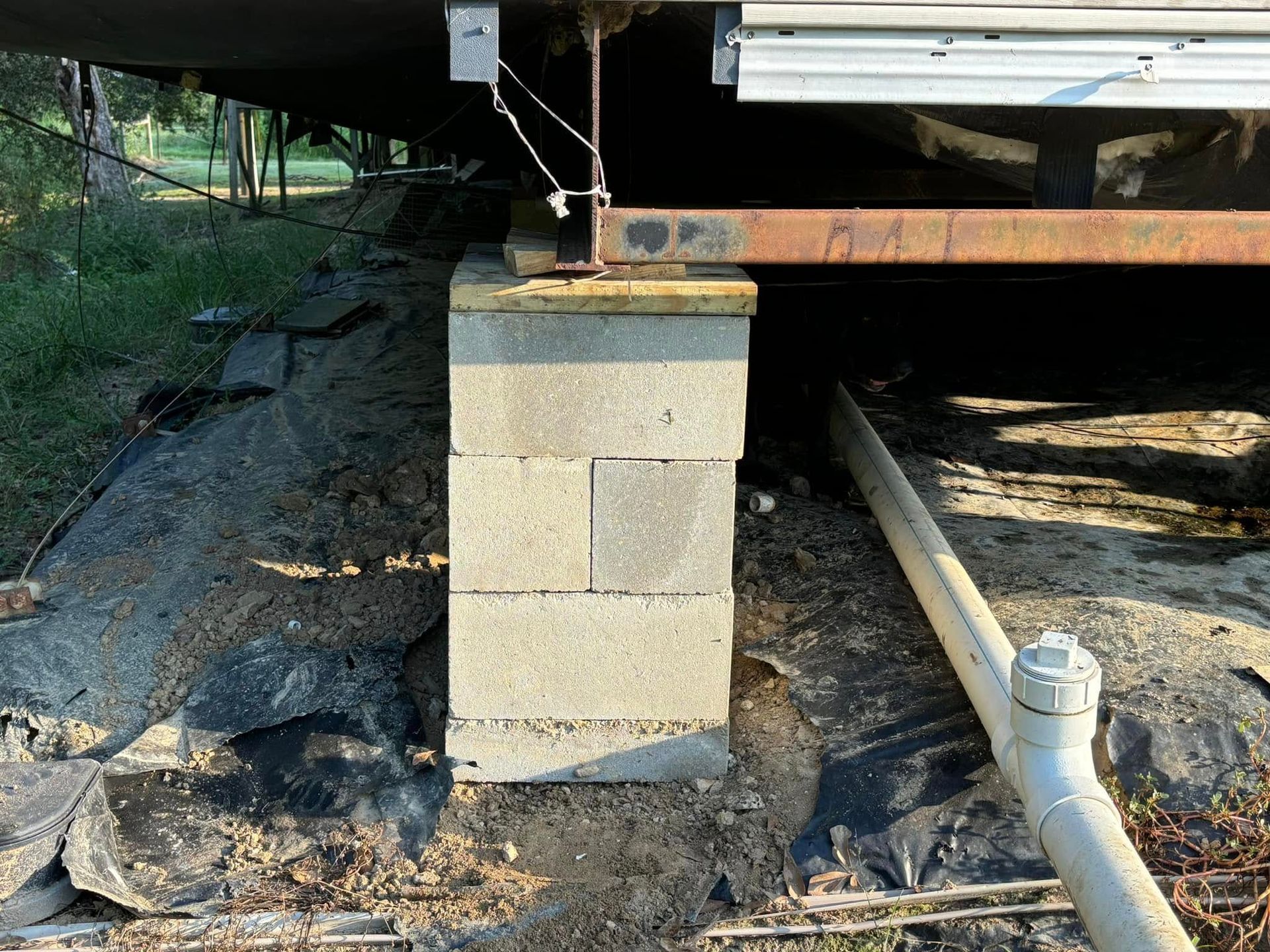 A concrete block is sitting in the dirt next to a pipe.