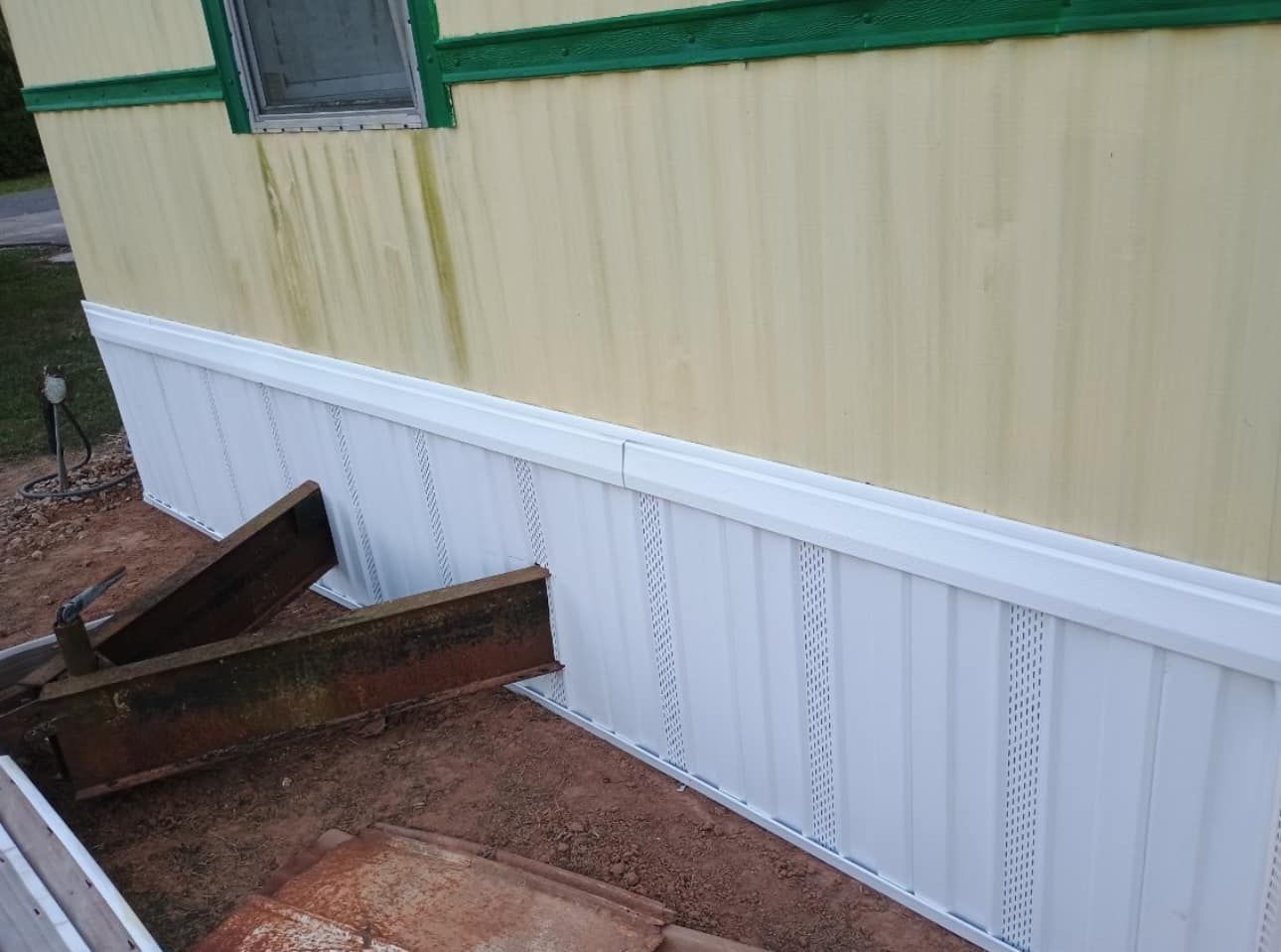 A mobile home with a white siding and a green trim.
