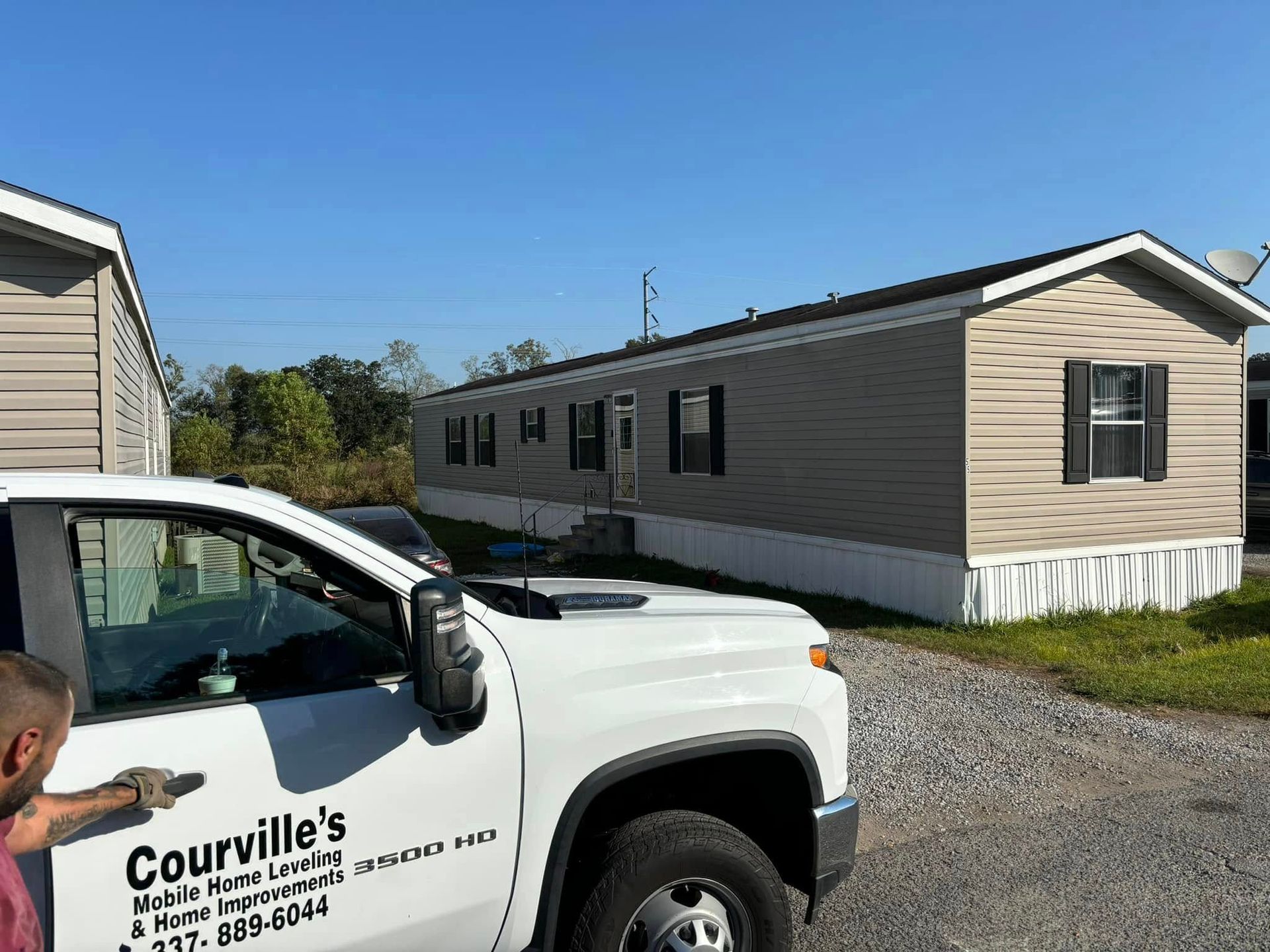 A white truck is parked in front of a mobile home.