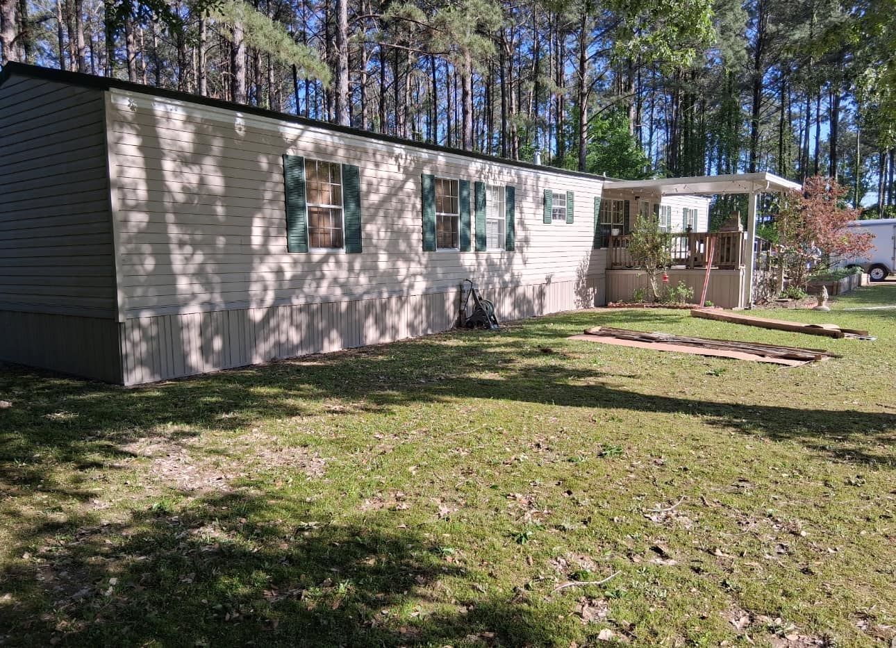 A mobile home is sitting in the middle of a lush green field.