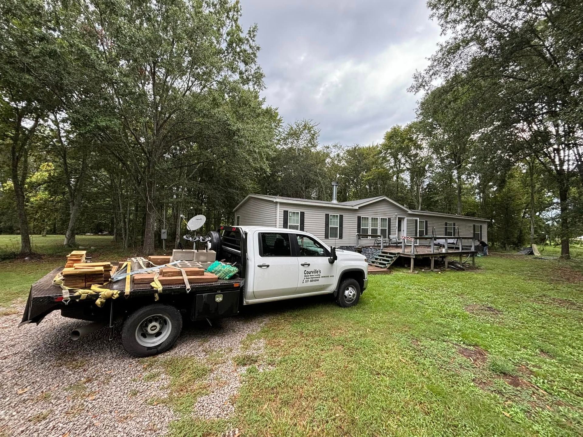 A white truck is parked in front of a mobile home.