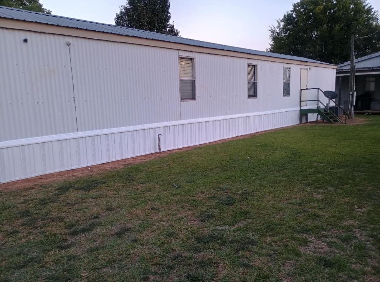 A white mobile home with a white fence in front of it.