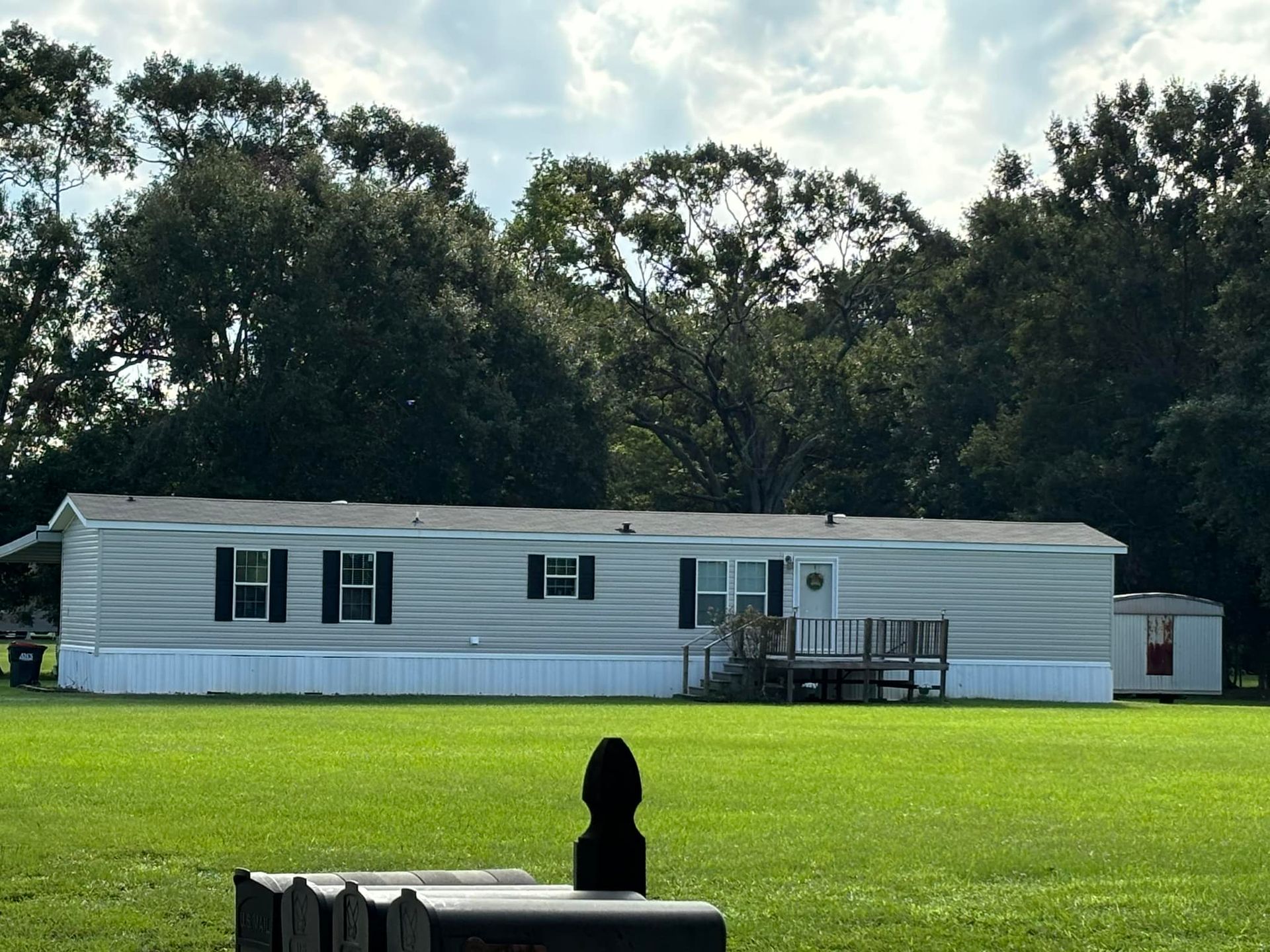 A mobile home sits in the middle of a lush green field