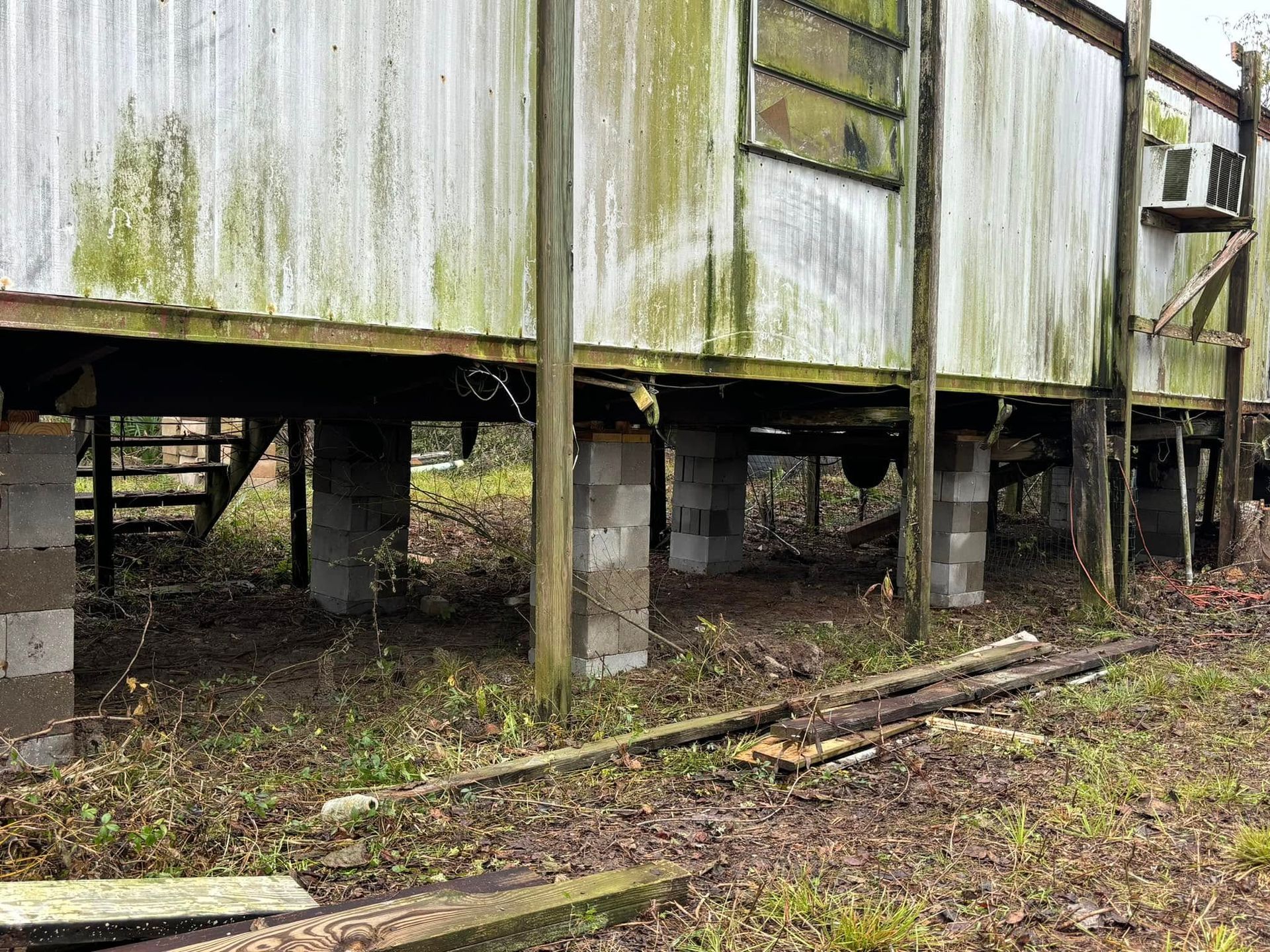 A very old building is sitting on stilts in the middle of a field.