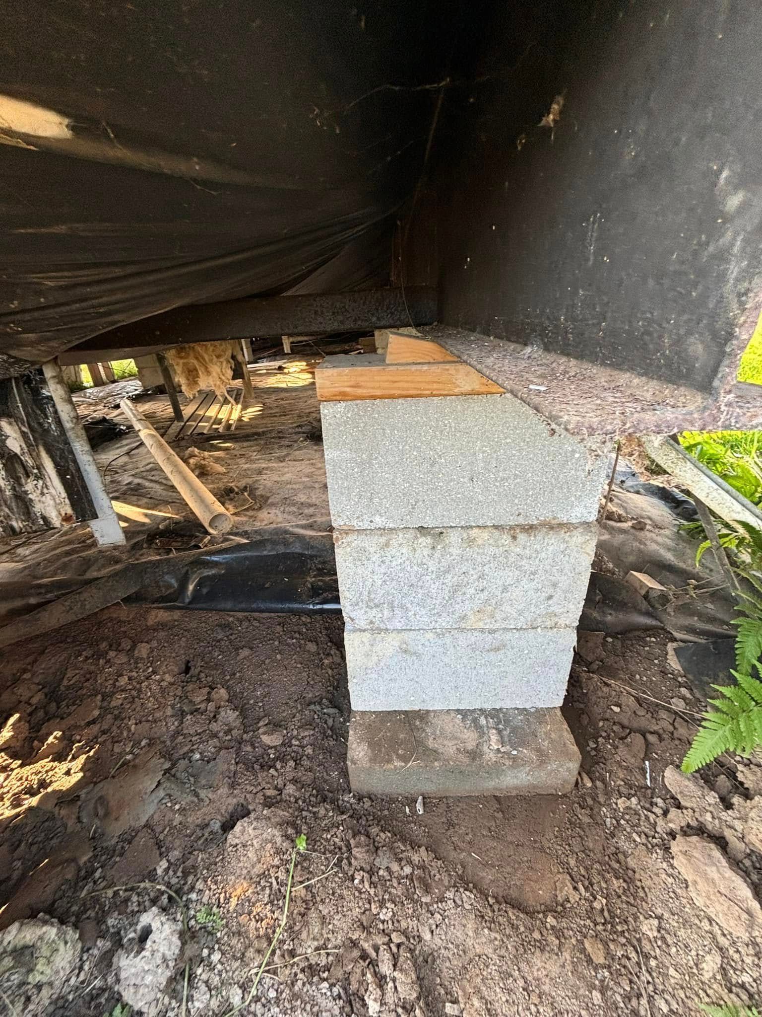 A stack of concrete blocks sitting on top of a pile of dirt under a building.
