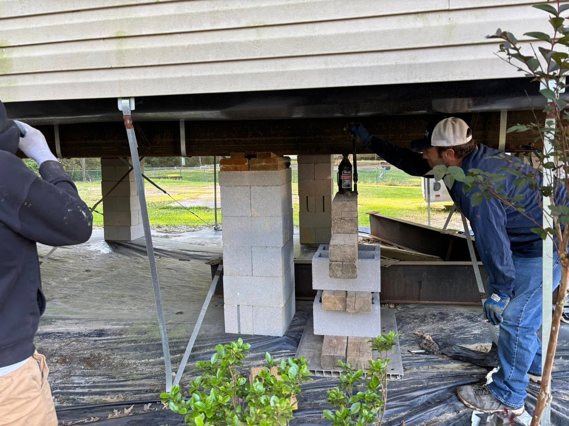 A couple of men are working under a house.