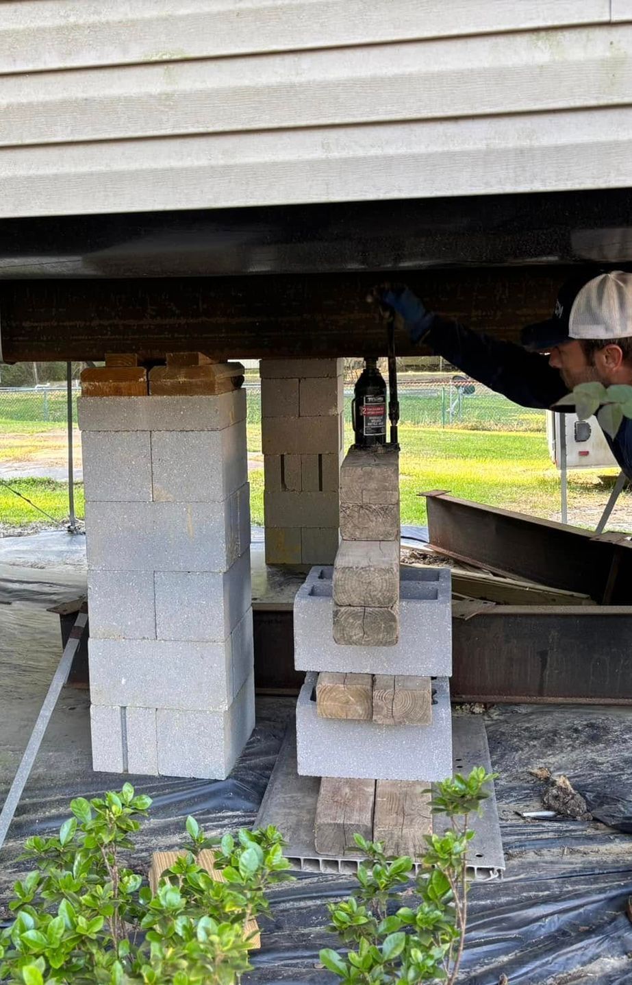 A man is working on a concrete pillar under a house.