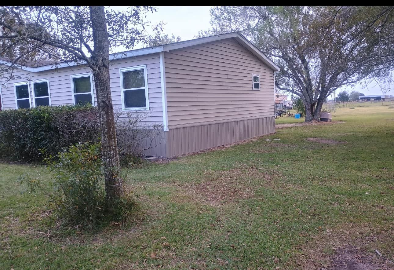 A mobile home is sitting in the middle of a grassy field.