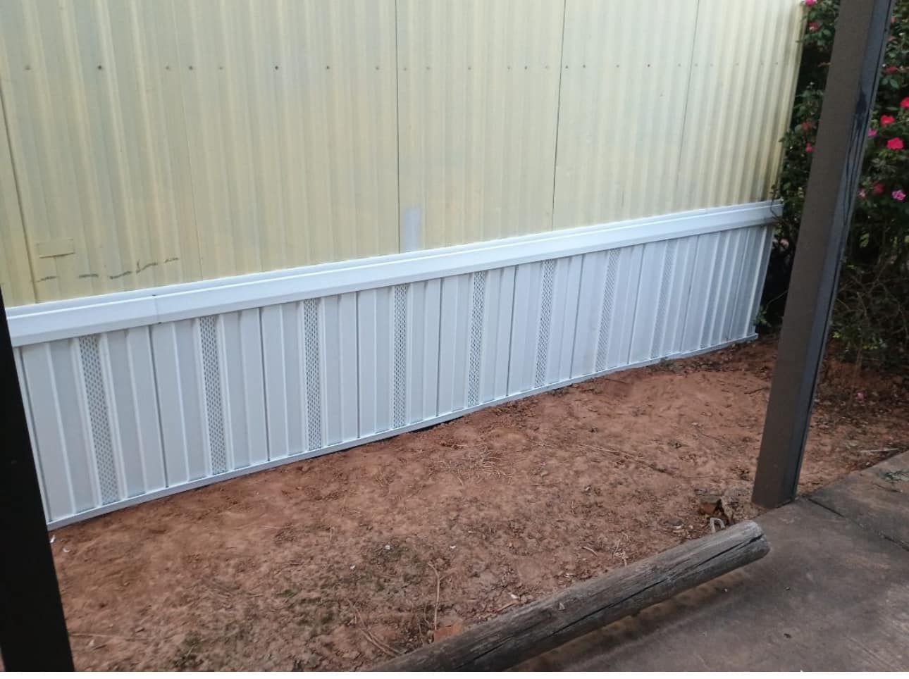 A white fence is sitting next to a yellow wall.