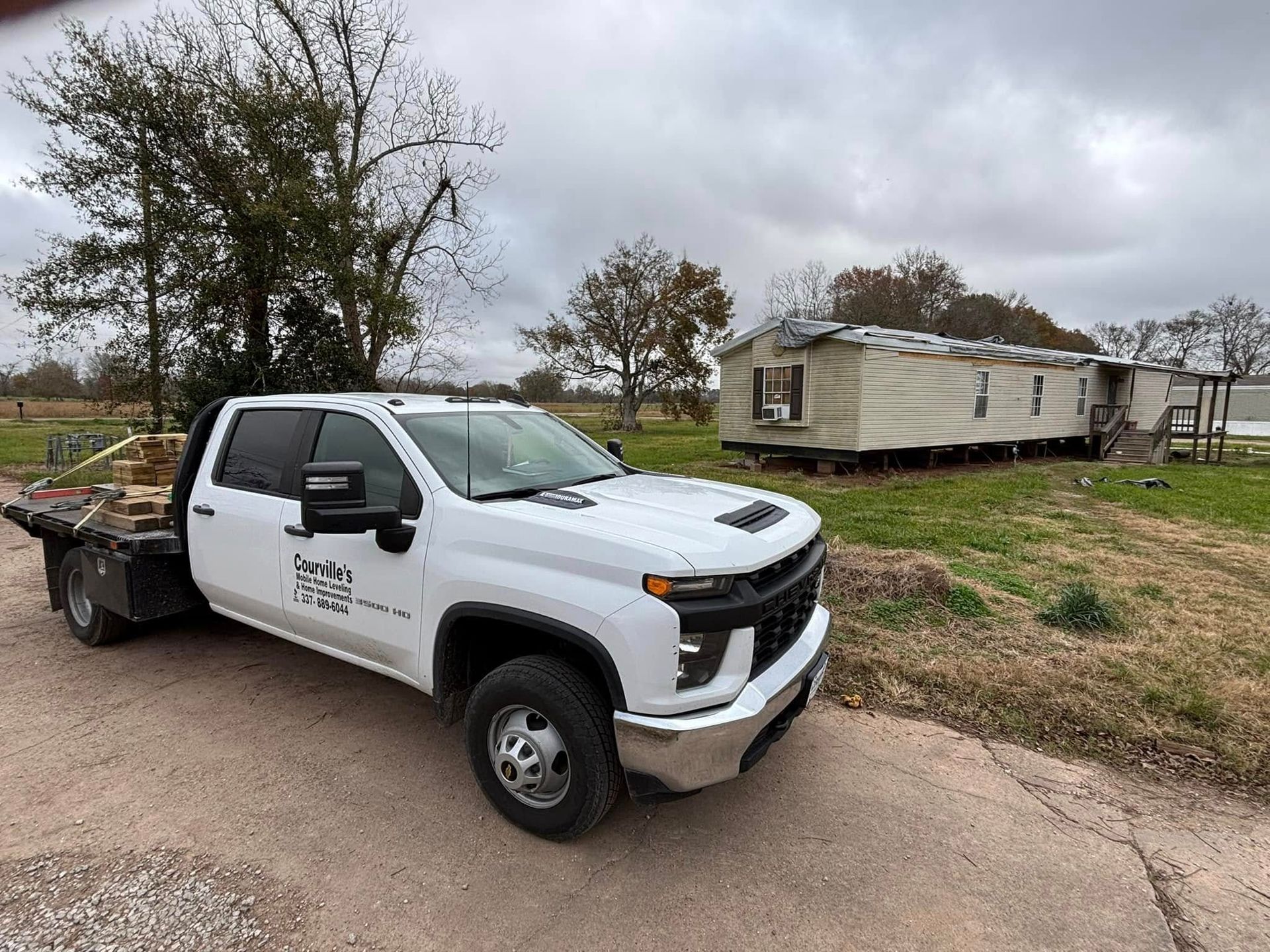 A white tow truck is parked in front of a mobile home.