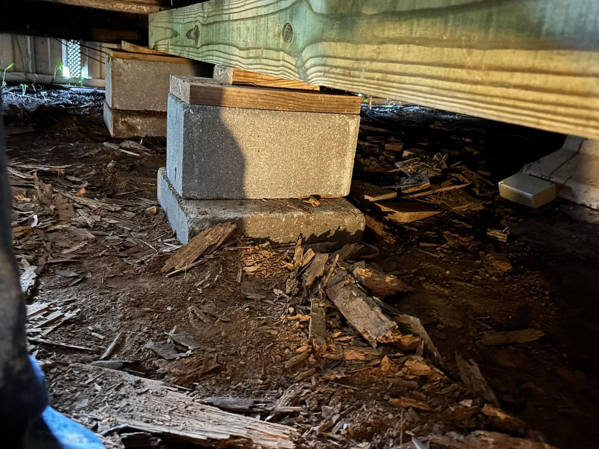 A concrete block is sitting on the ground under a wooden structure.