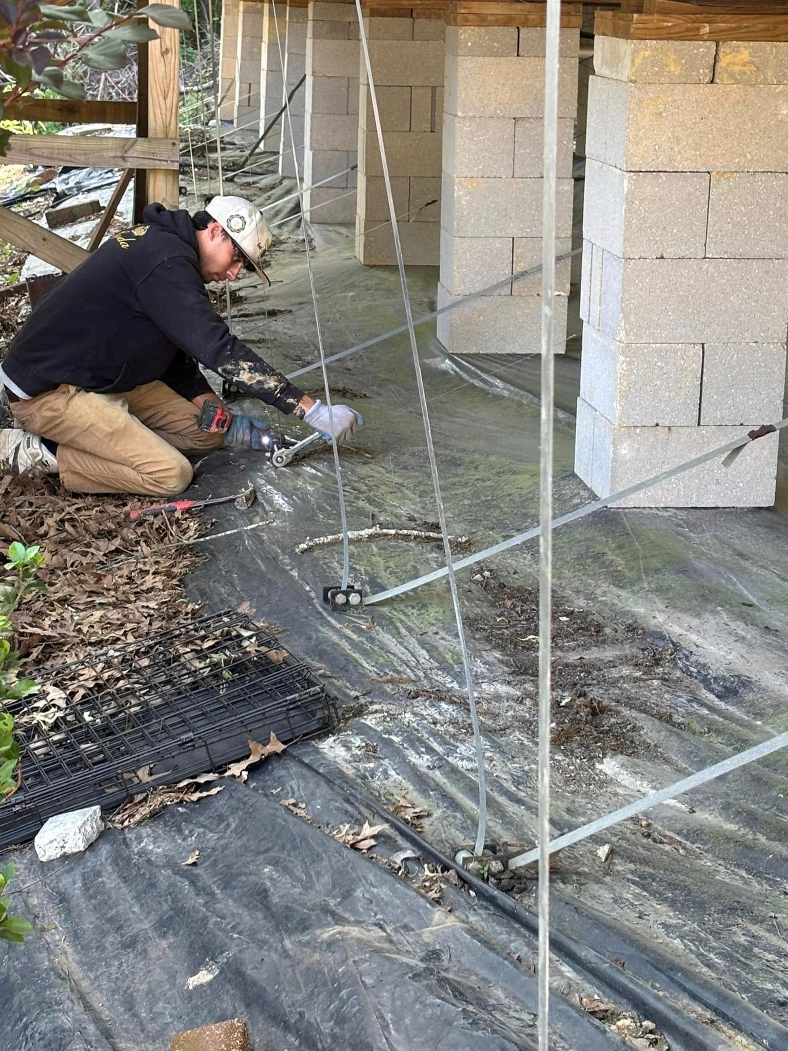 A man is kneeling down on the ground working on a construction site.