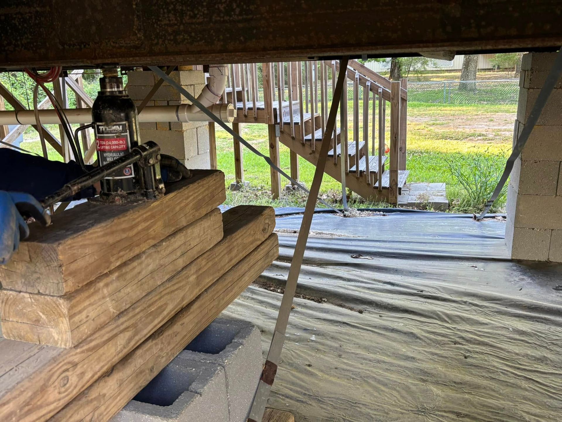 A stack of wood is sitting underneath a staircase.