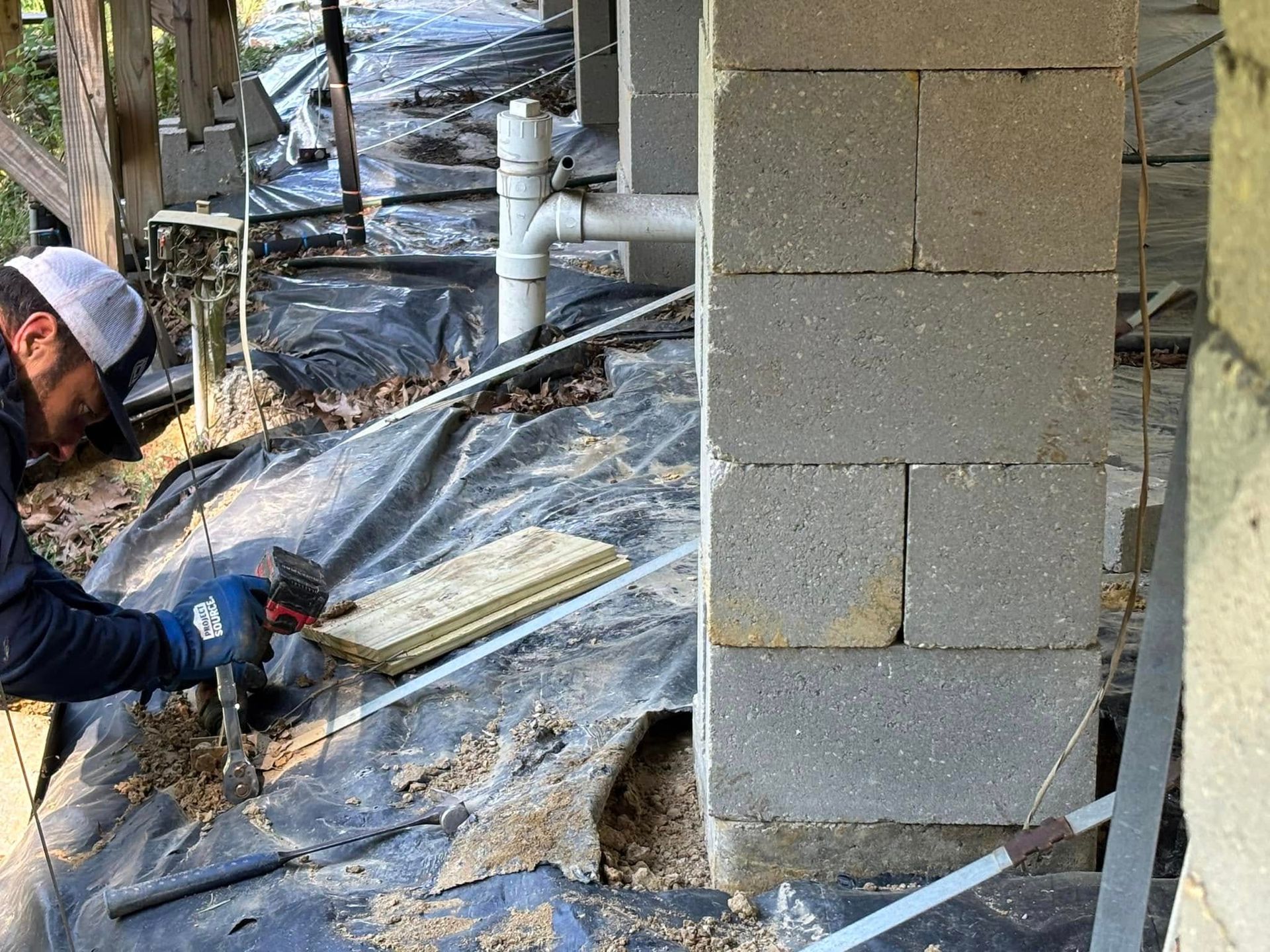 A man is working on a brick wall with a hammer.