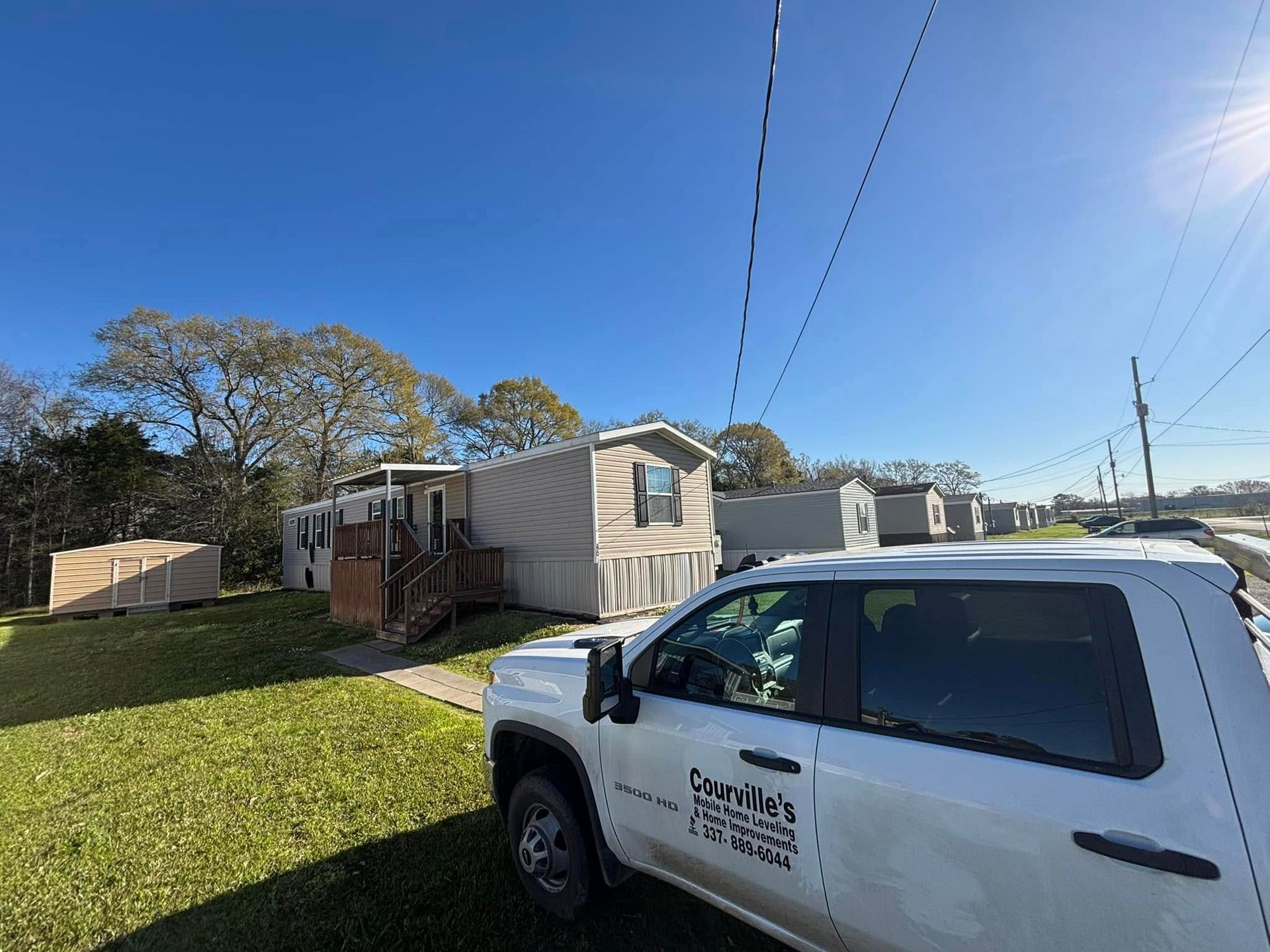 A white truck is parked in front of a mobile home.