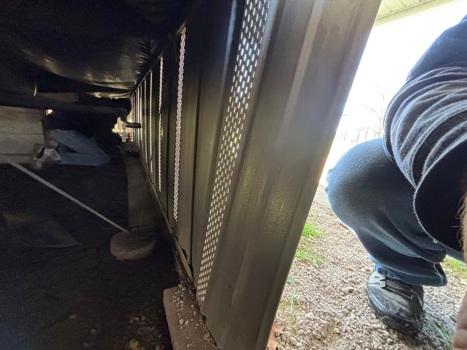 A person is kneeling down next to a metal wall.