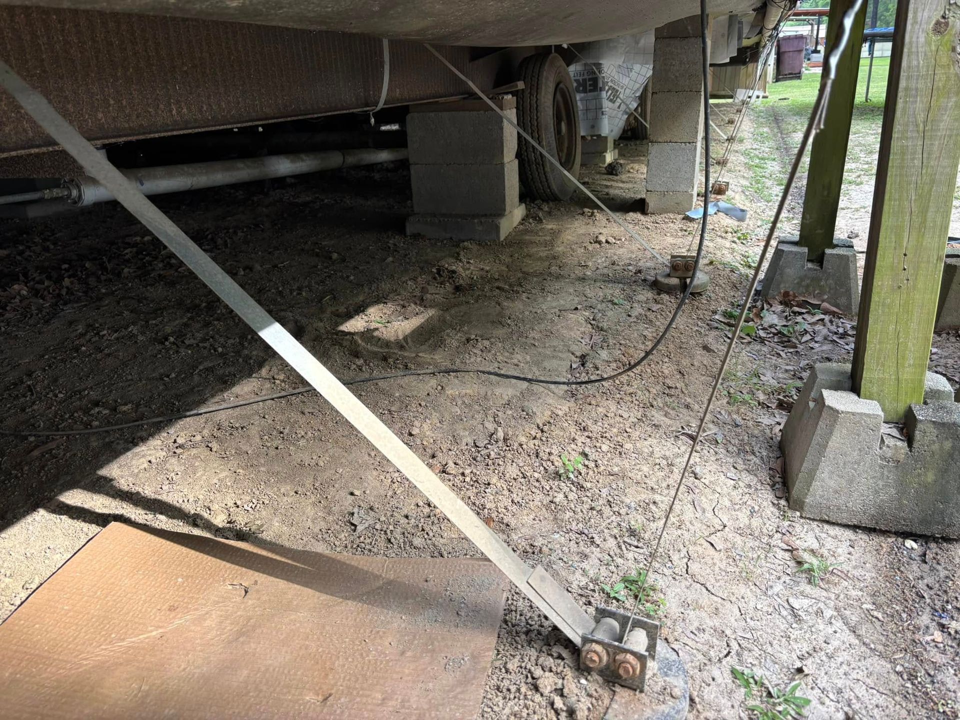 A metal pole is sitting on the ground under a trailer.