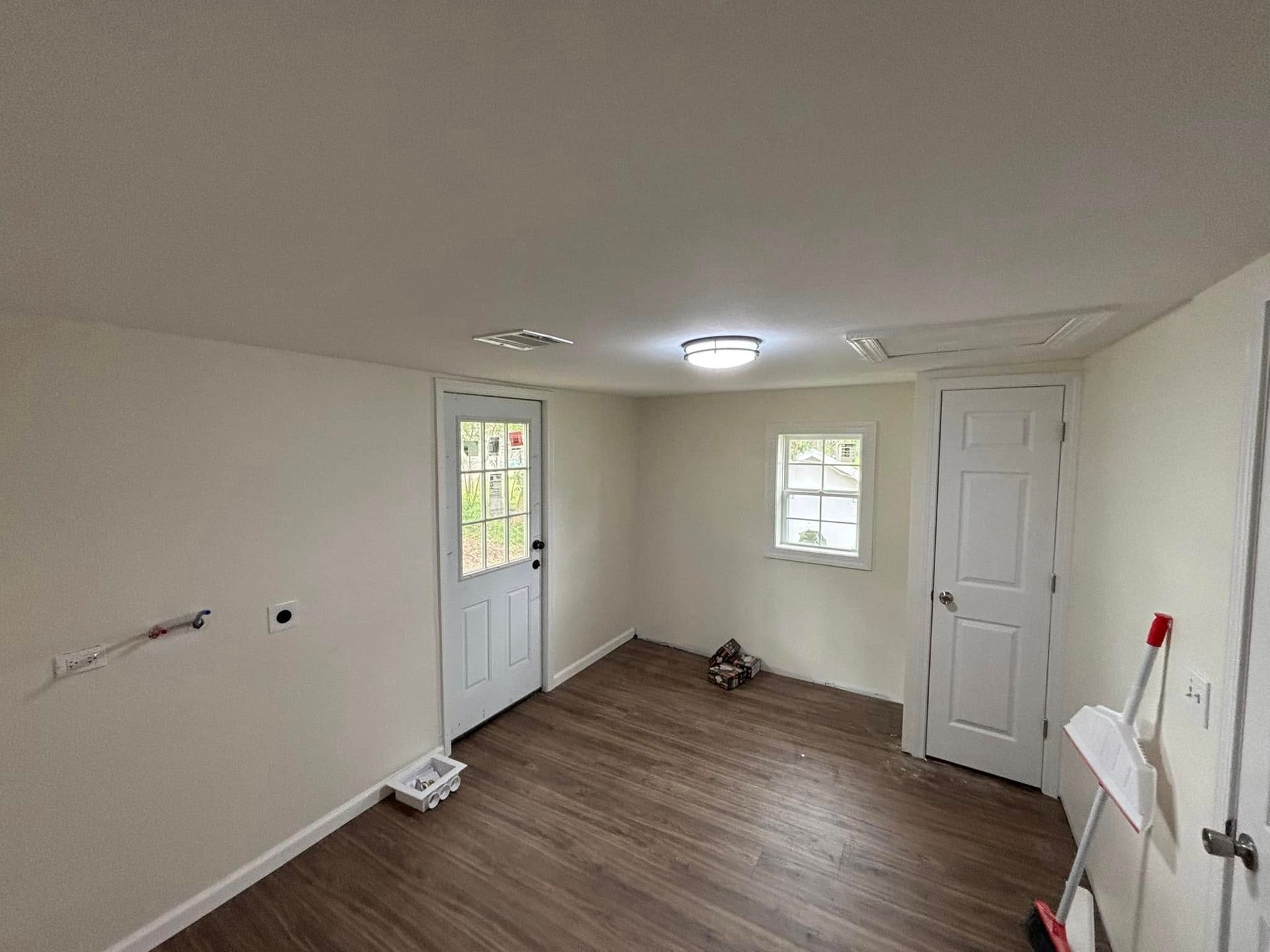 A room with hardwood floors , white walls and a door.