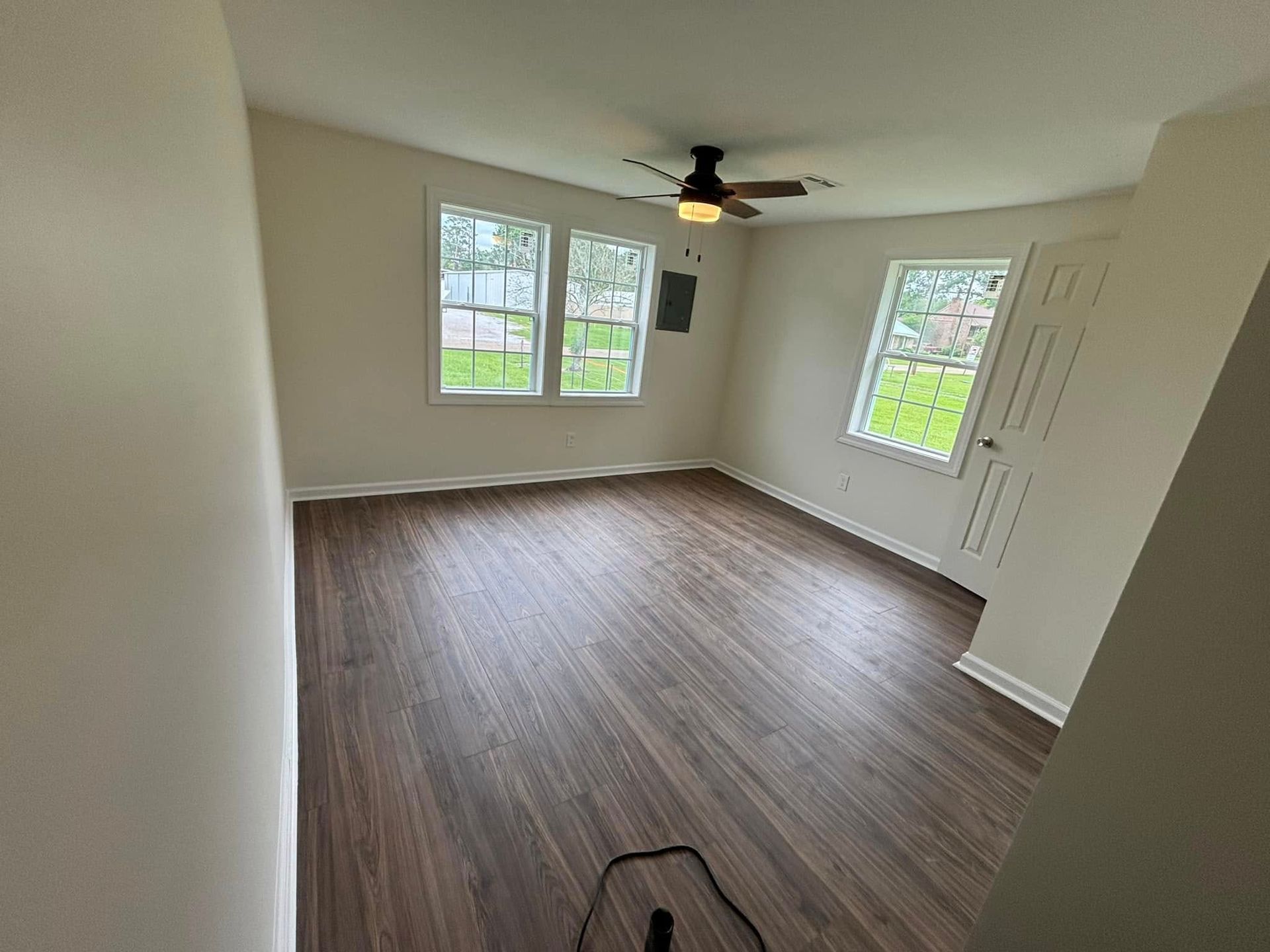 An empty living room with hardwood floors and a ceiling fan.