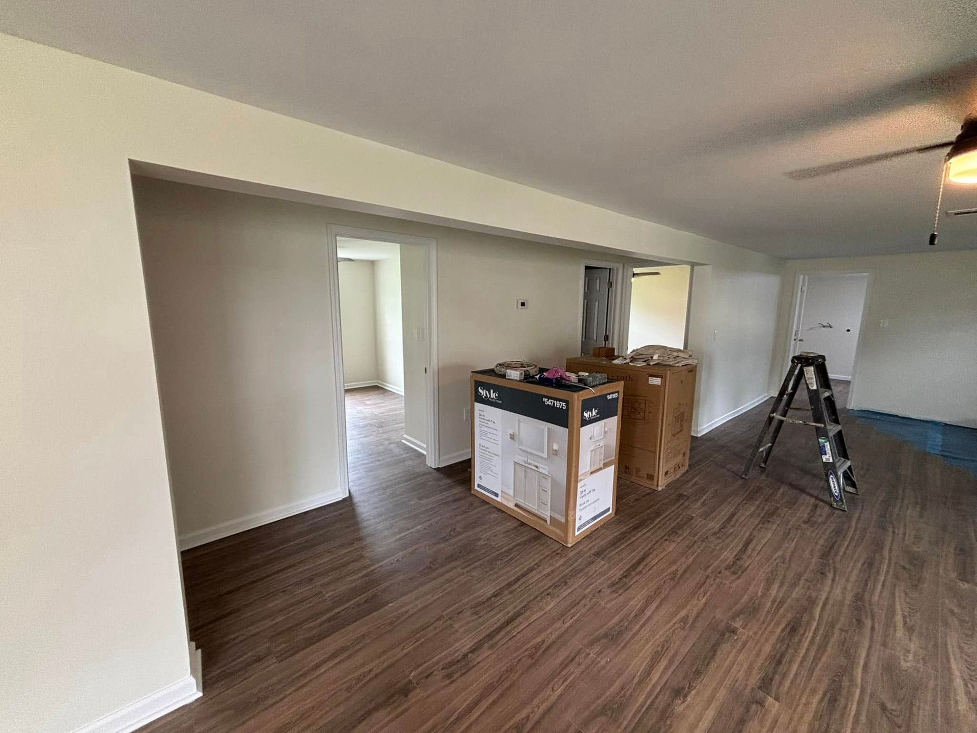 A living room with hardwood floors and white walls is being remodeled.