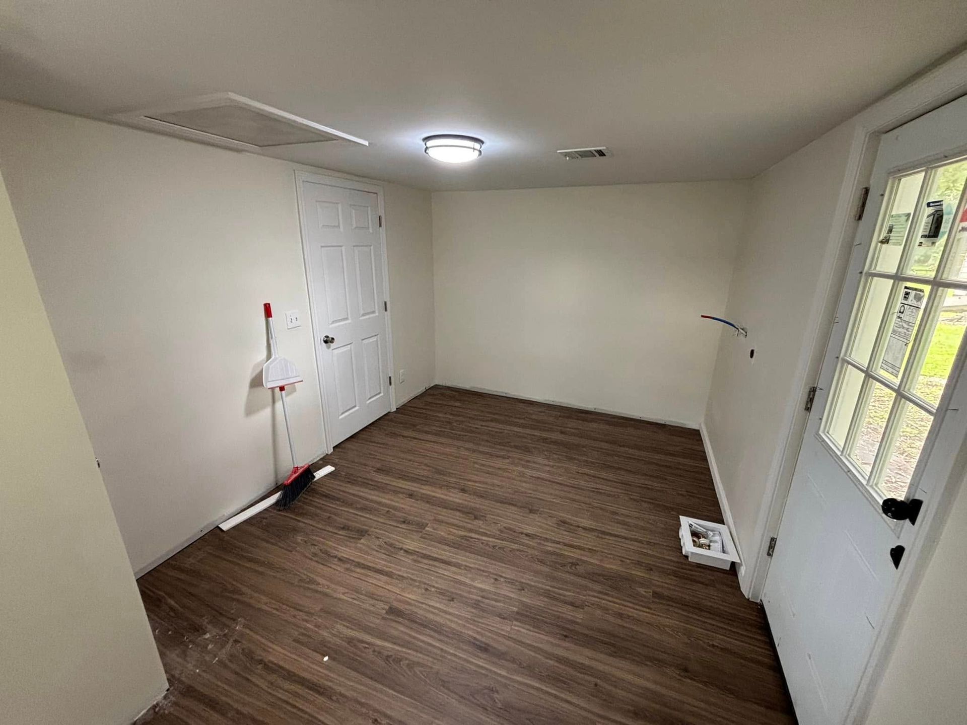 A room with hardwood floors , white walls and a door.