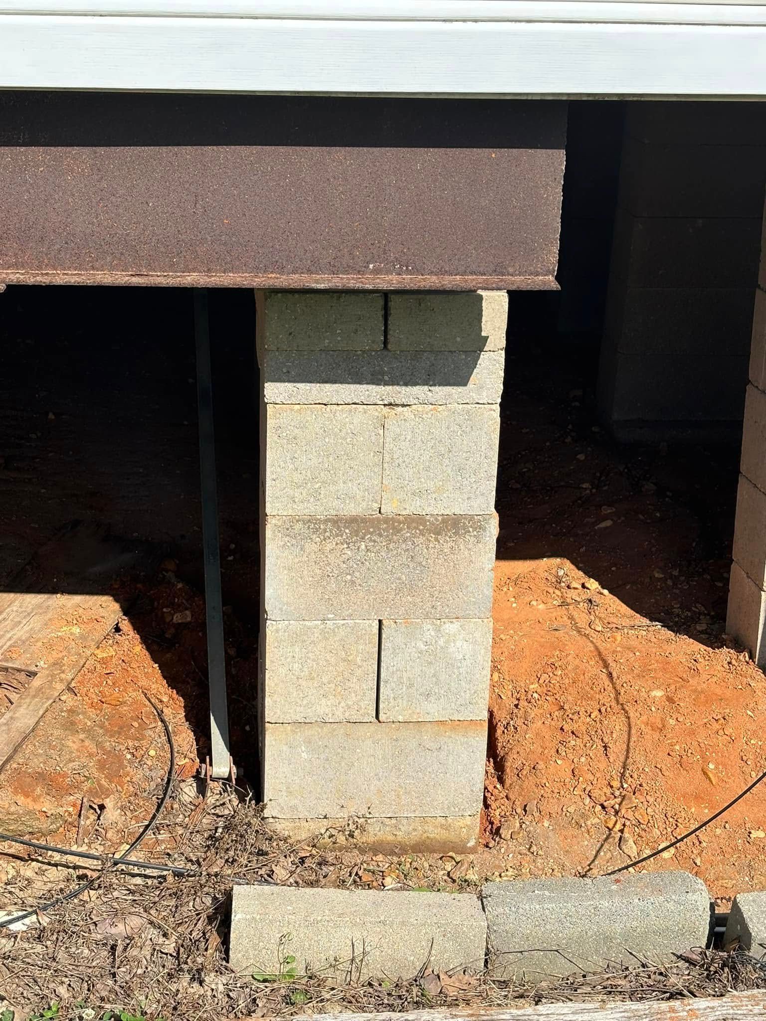 A concrete block is sitting under a metal beam.