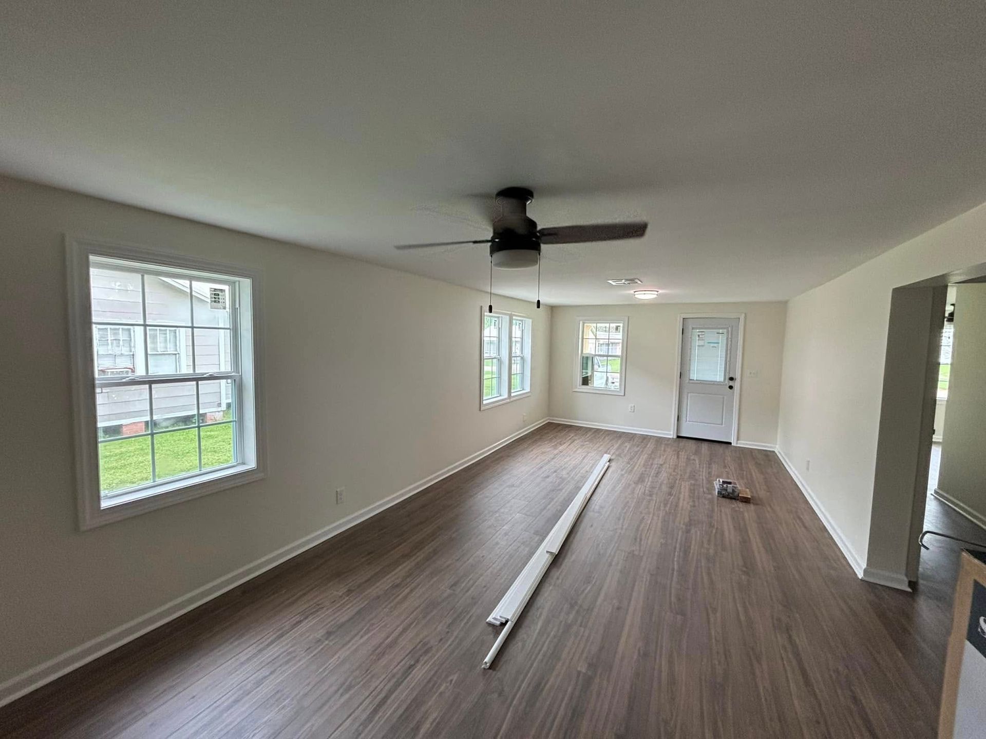 An empty living room with hardwood floors and a ceiling fan.